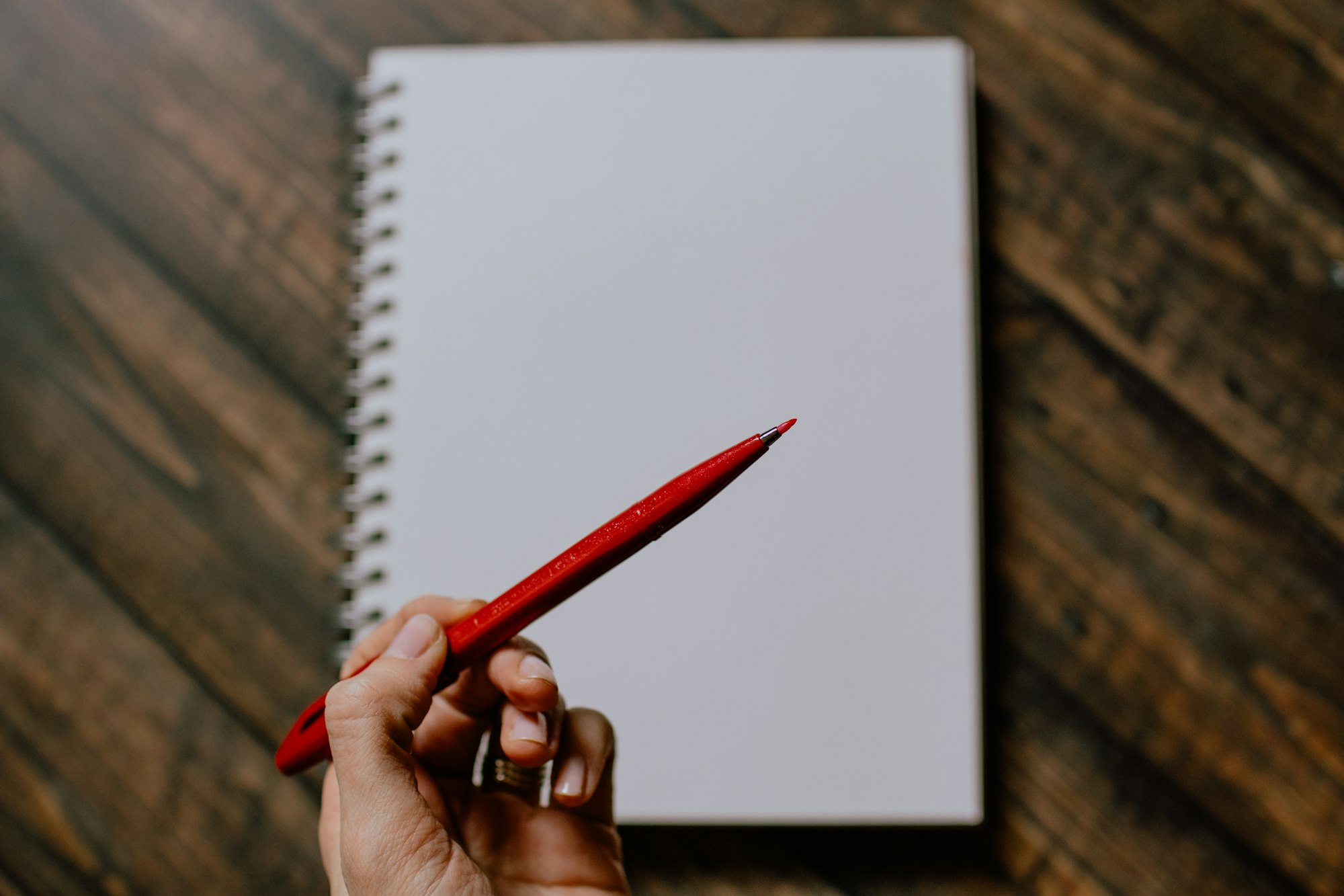 A hand marking up paper with a red pencil