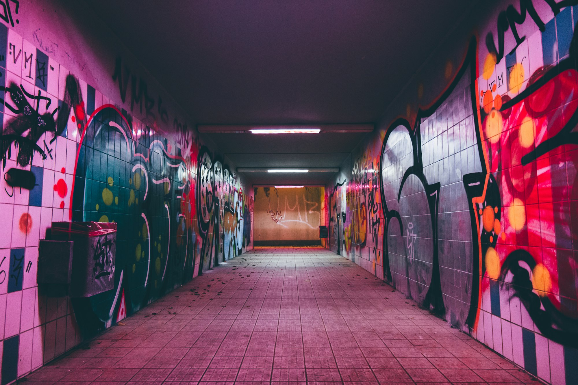 An empty tunnel pathway with graffiti-covered walls