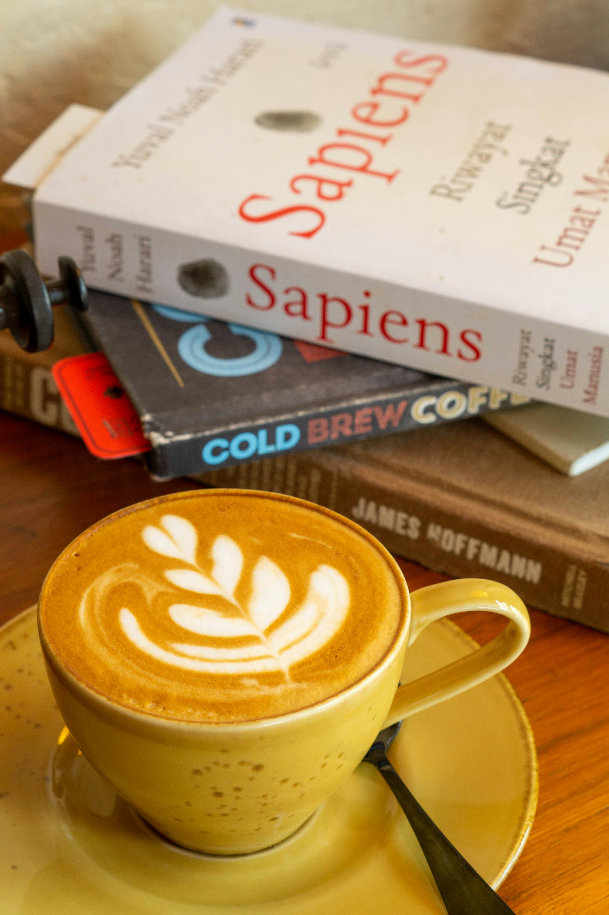 A cappuccino on a saucer next to a stack of books
