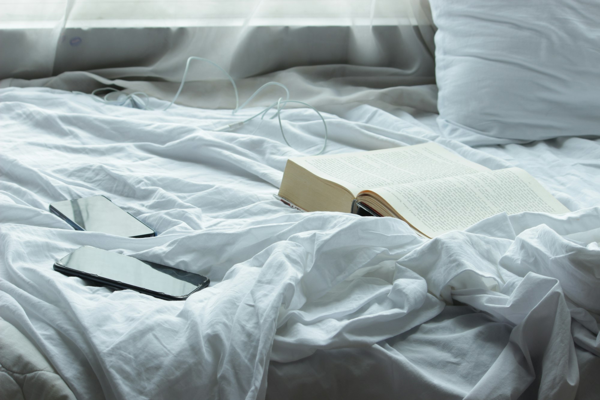 An open book laying on a bed with white sheets