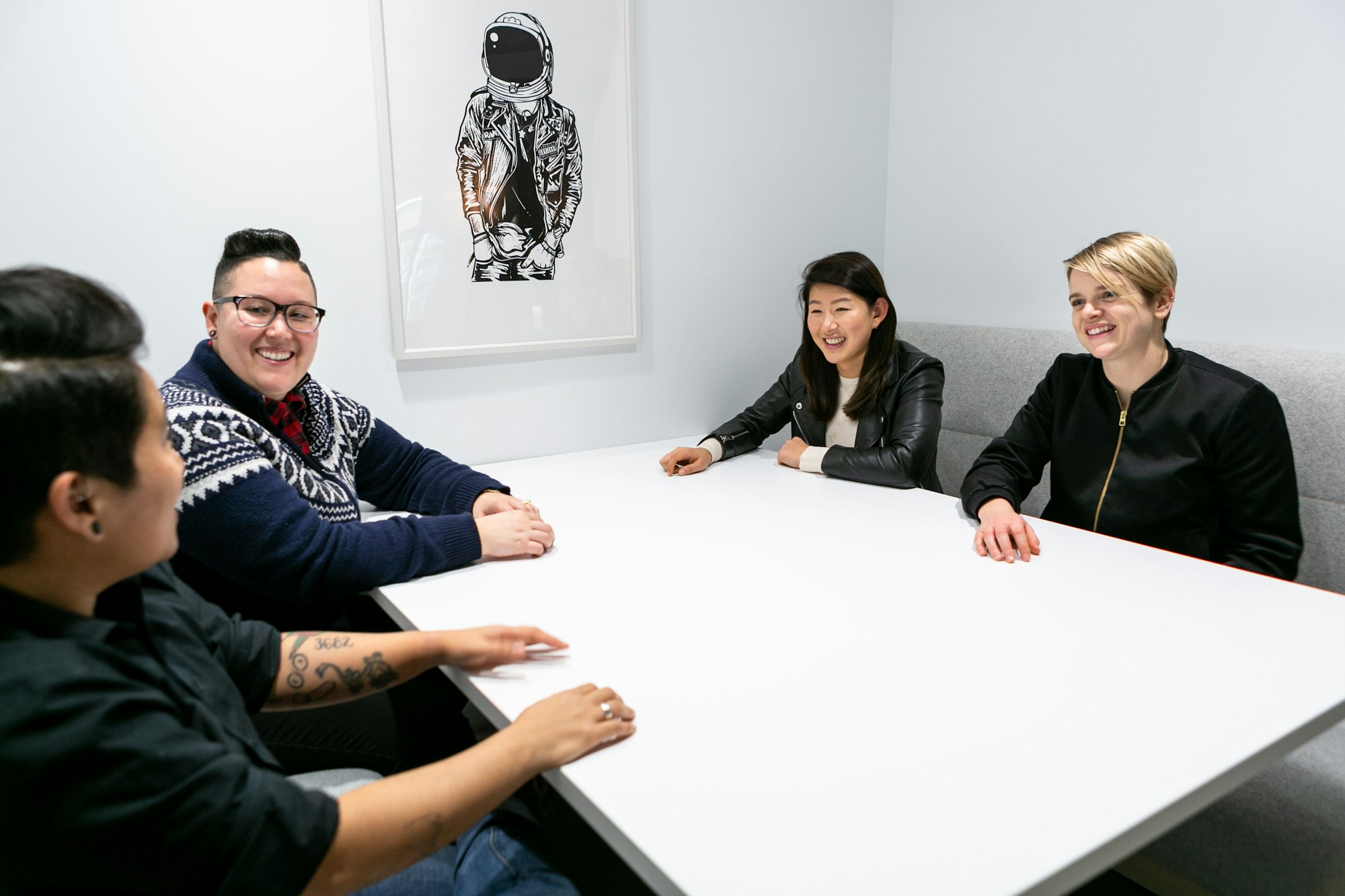 Group of four people smiling around a boardroom table