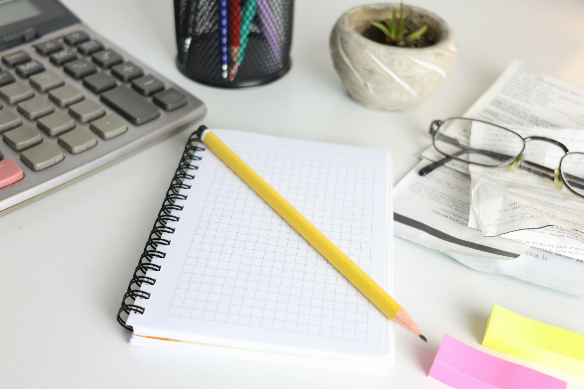 Desk with calculator, notebook, pencil, and glasses