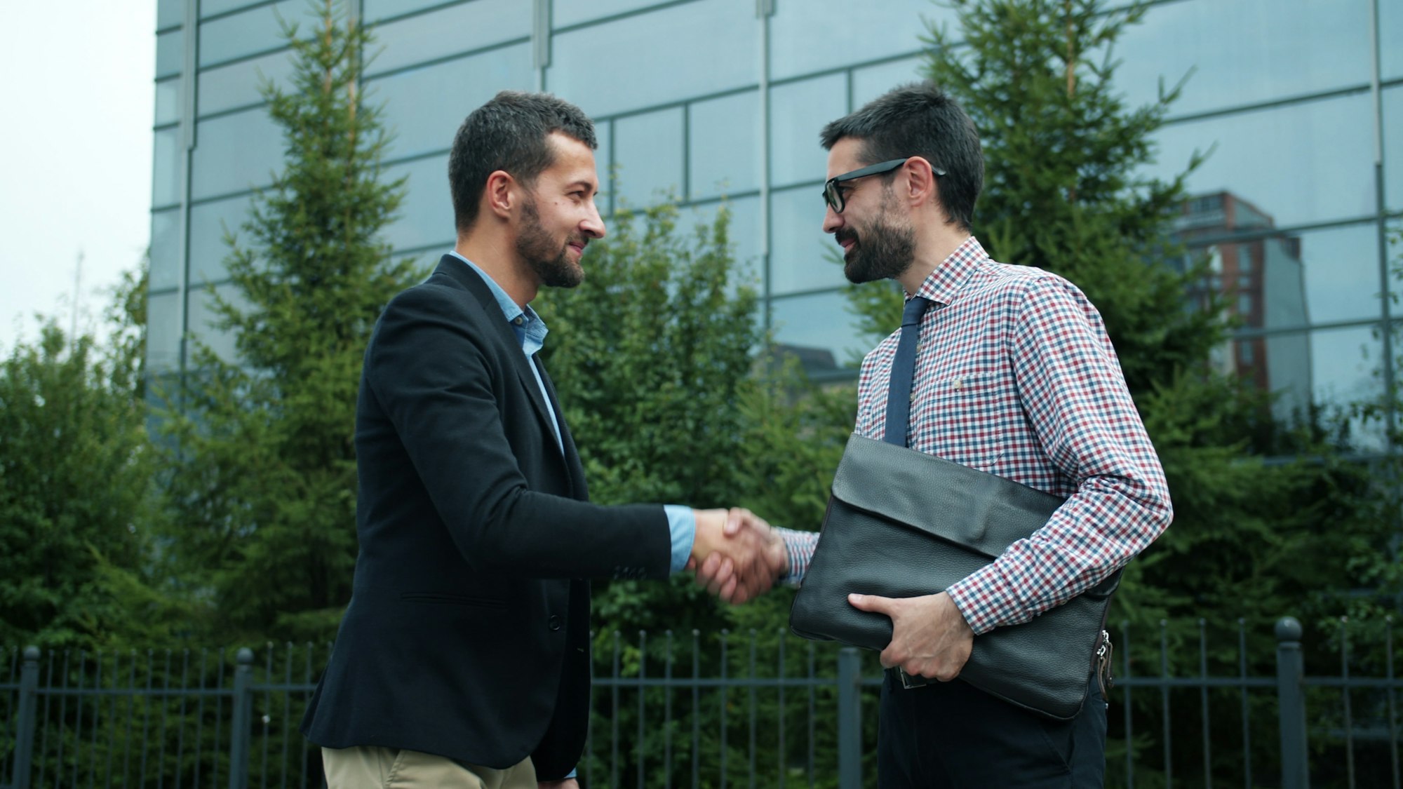 Two businessmen shaking hands outside a modern building