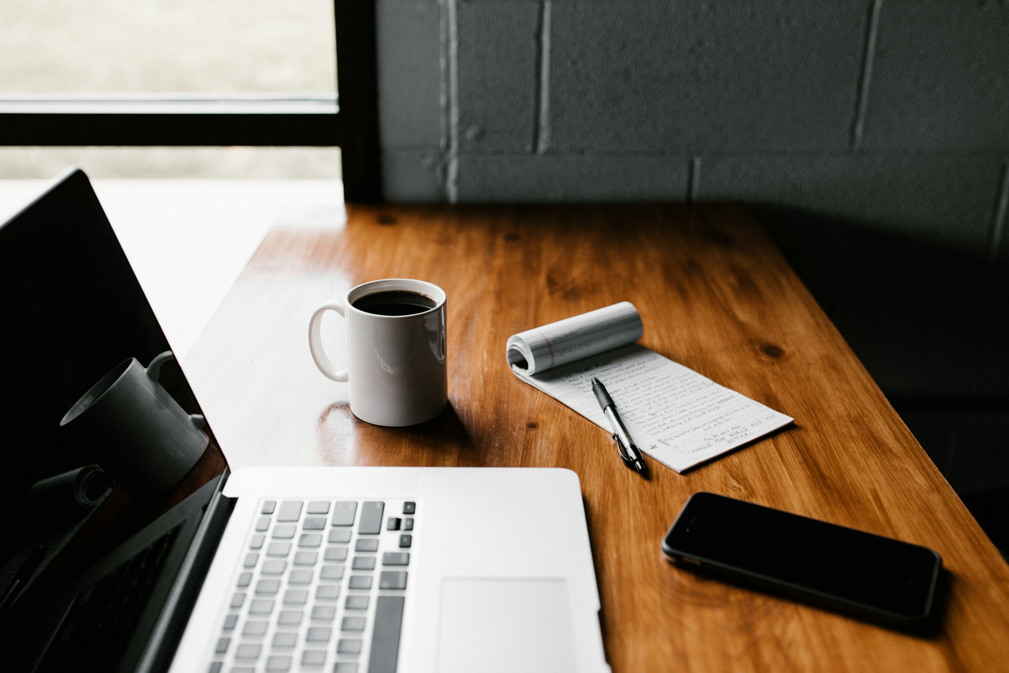 A tidy desk with a laptop, coffee mug, and phone