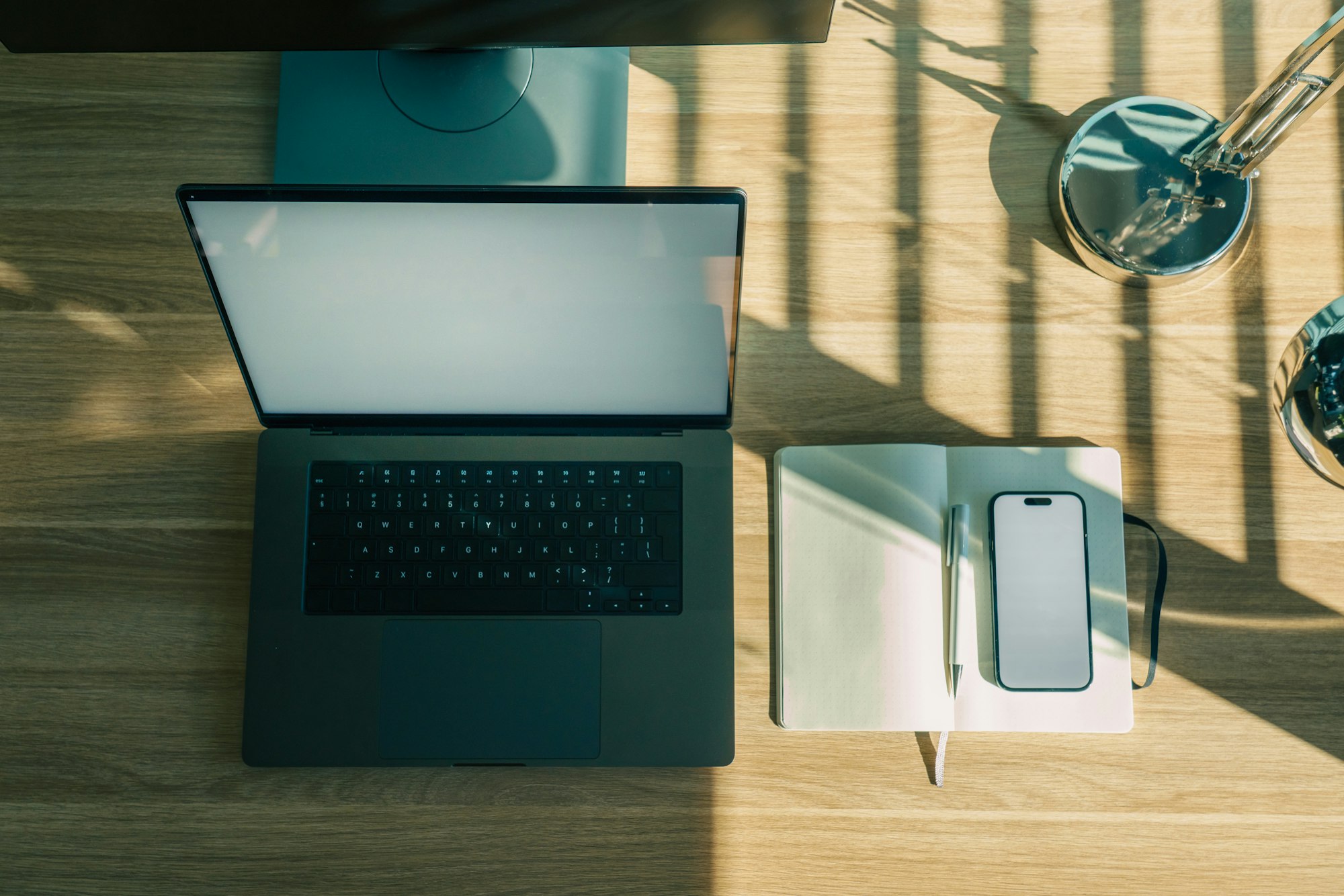 Laptop, phone, and notebook on a wooden desk