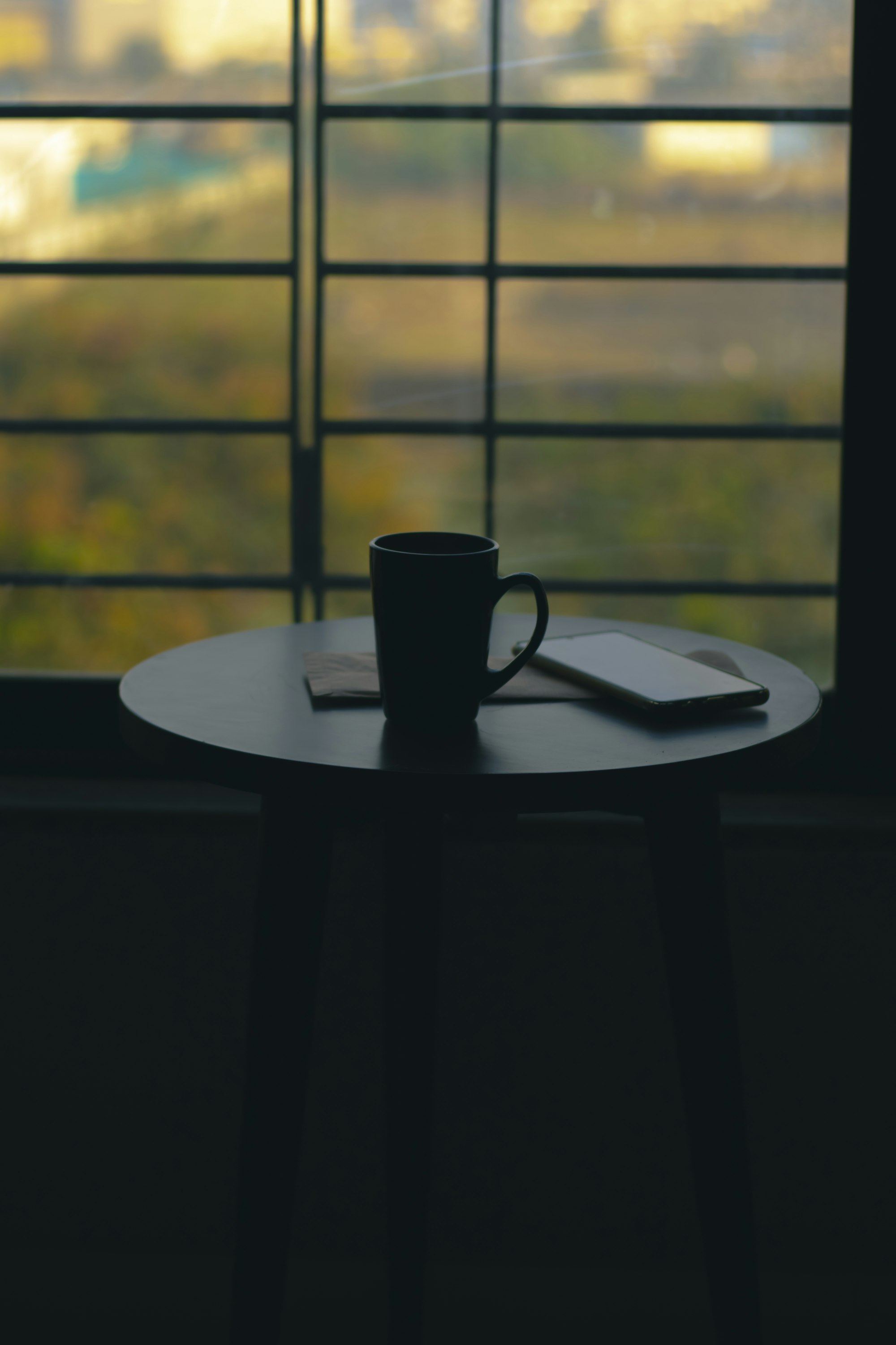 Coffee mug on a table next to a window with morning light