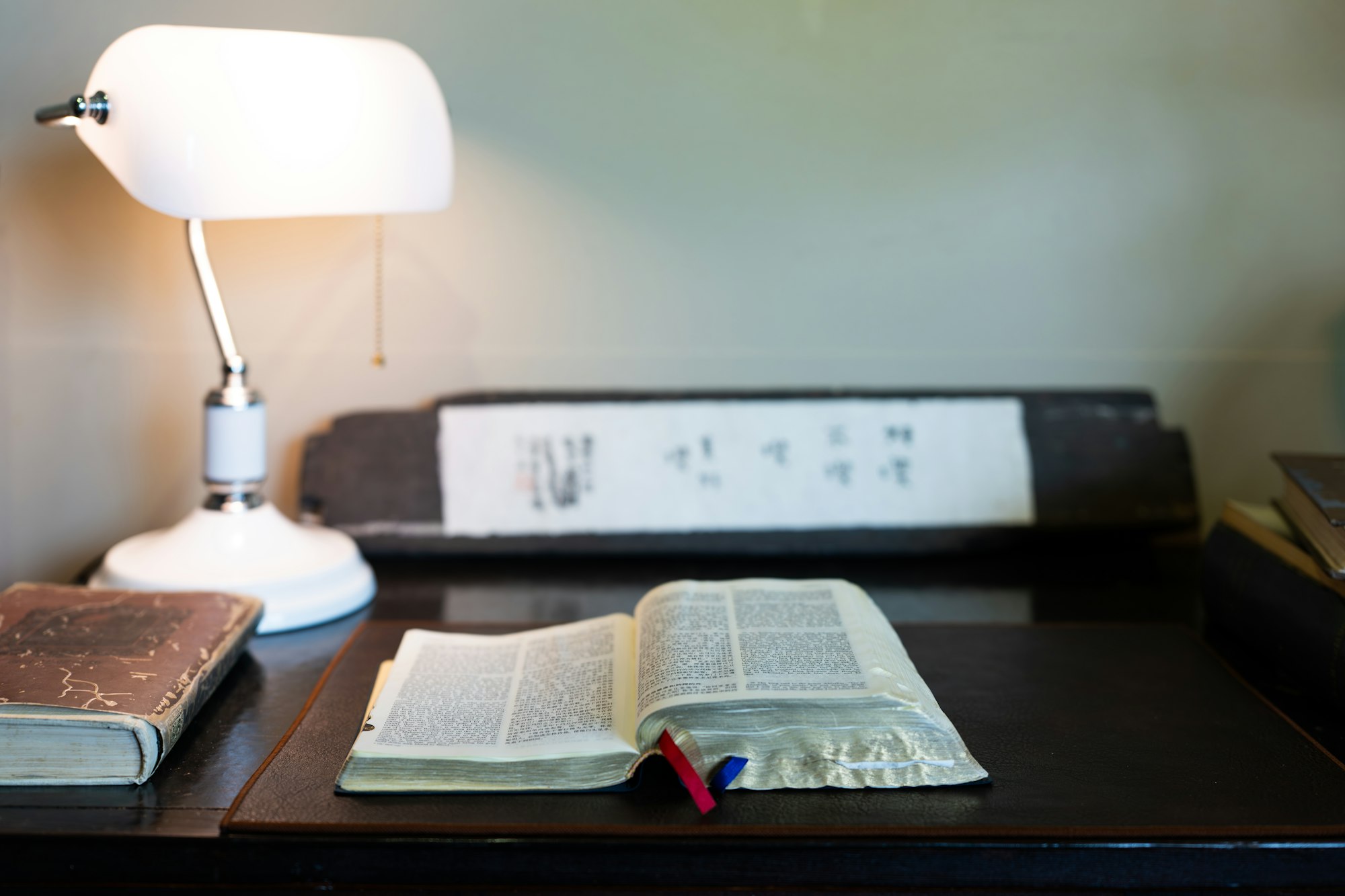 An open book resting on a desk beside a lamp