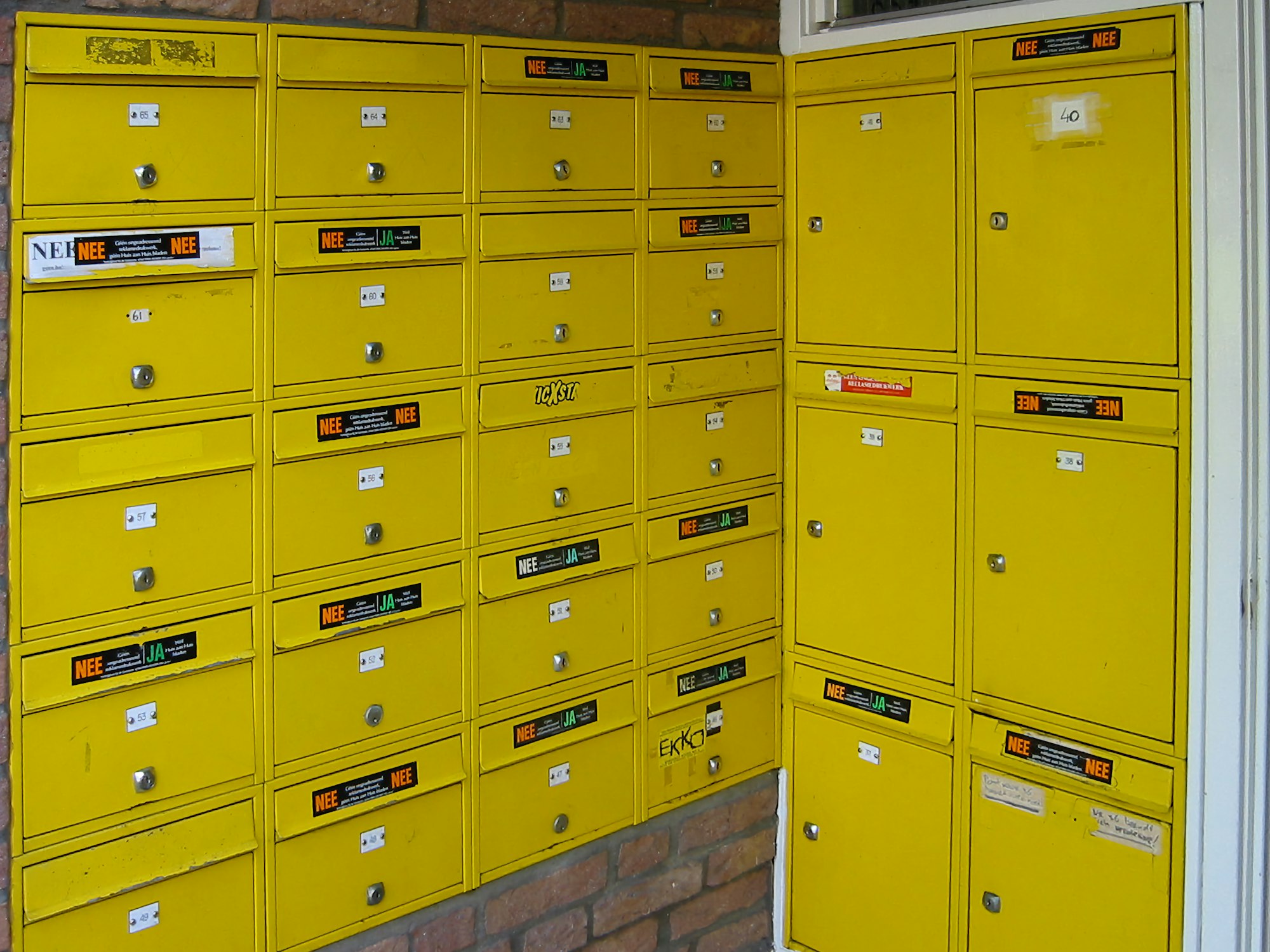 Yellow mail boxes sitting next to a brick wall