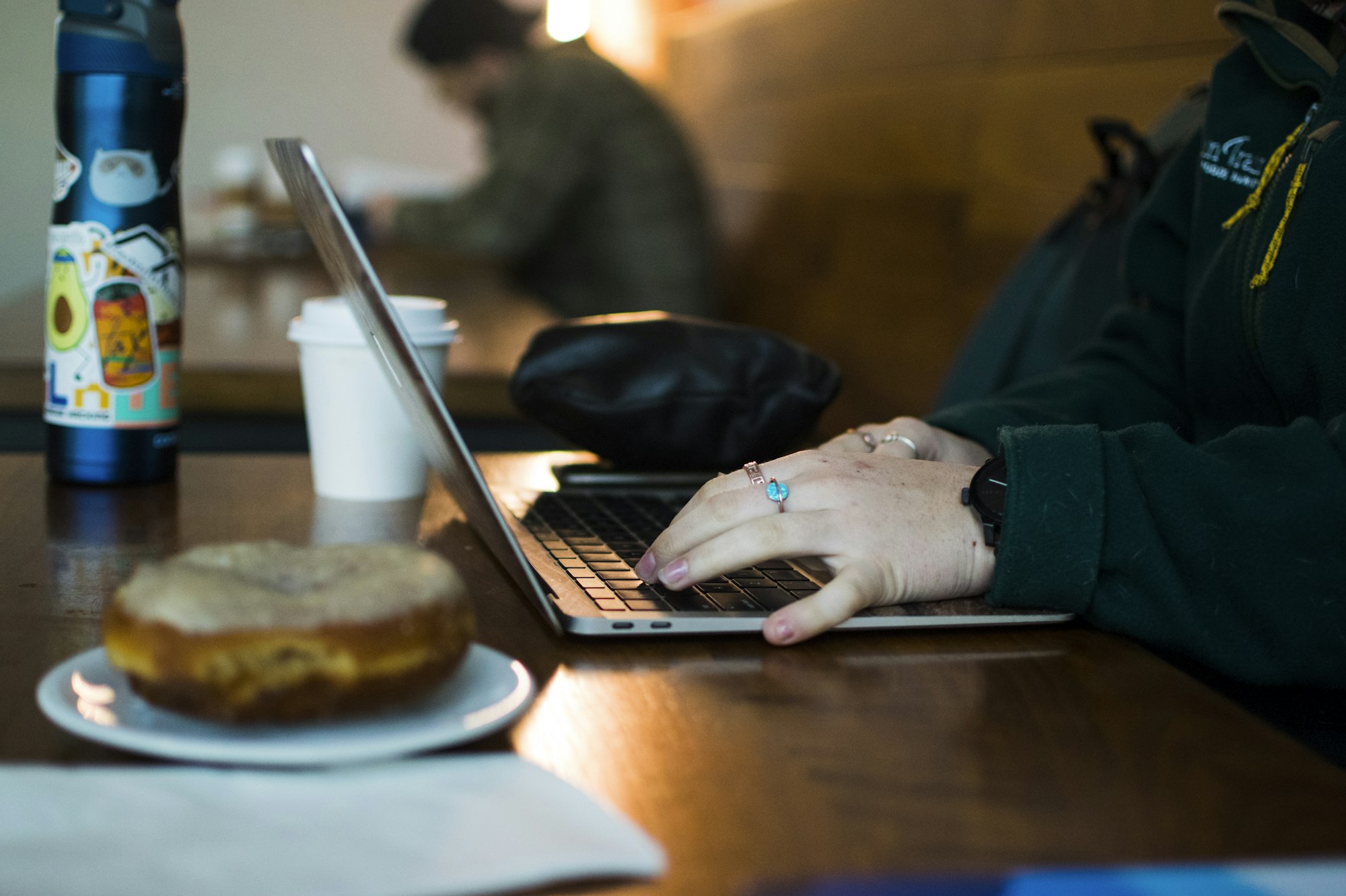 A person using a laptop at a wooden table