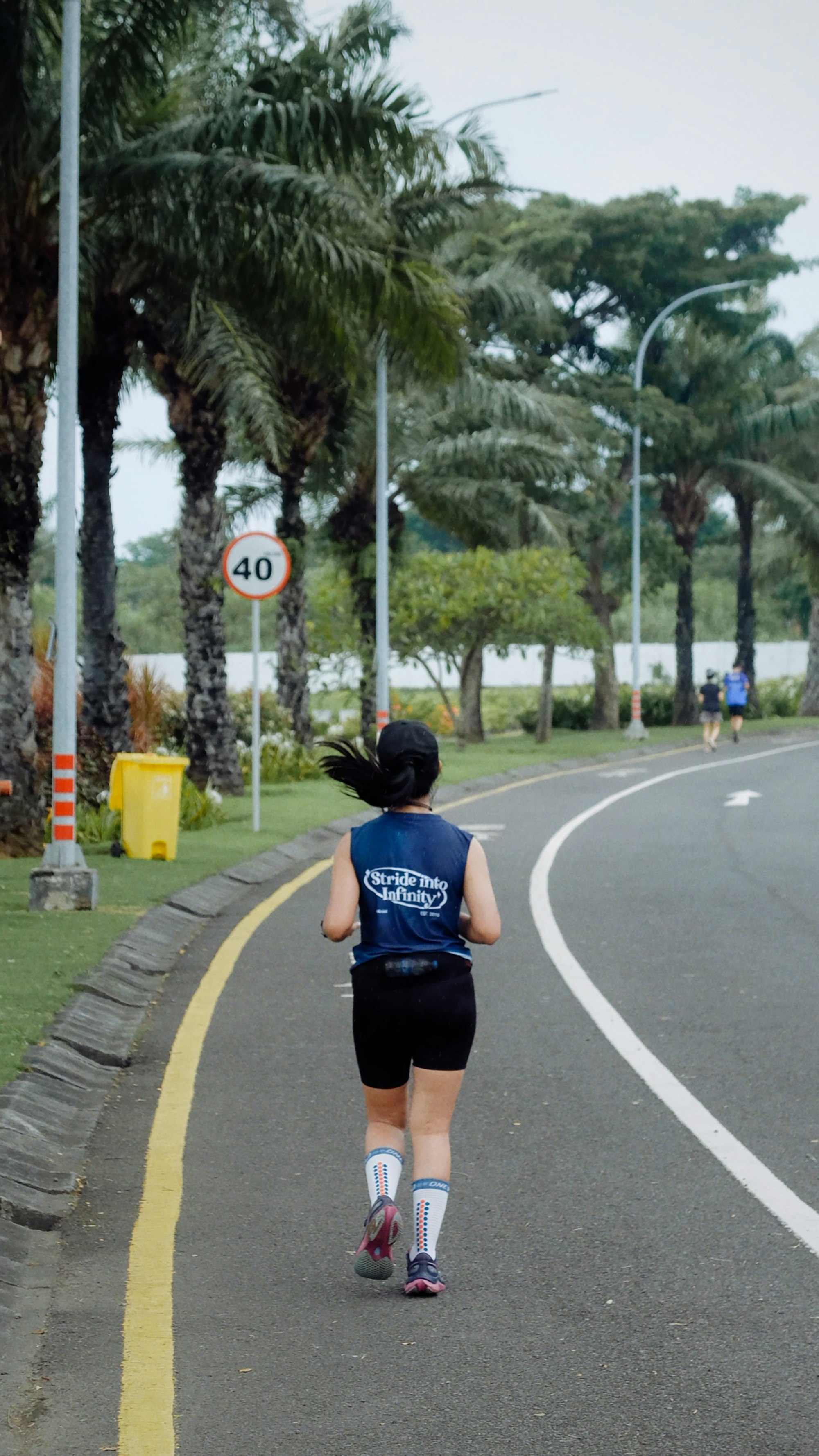 A woman running on a paved path with palm trees