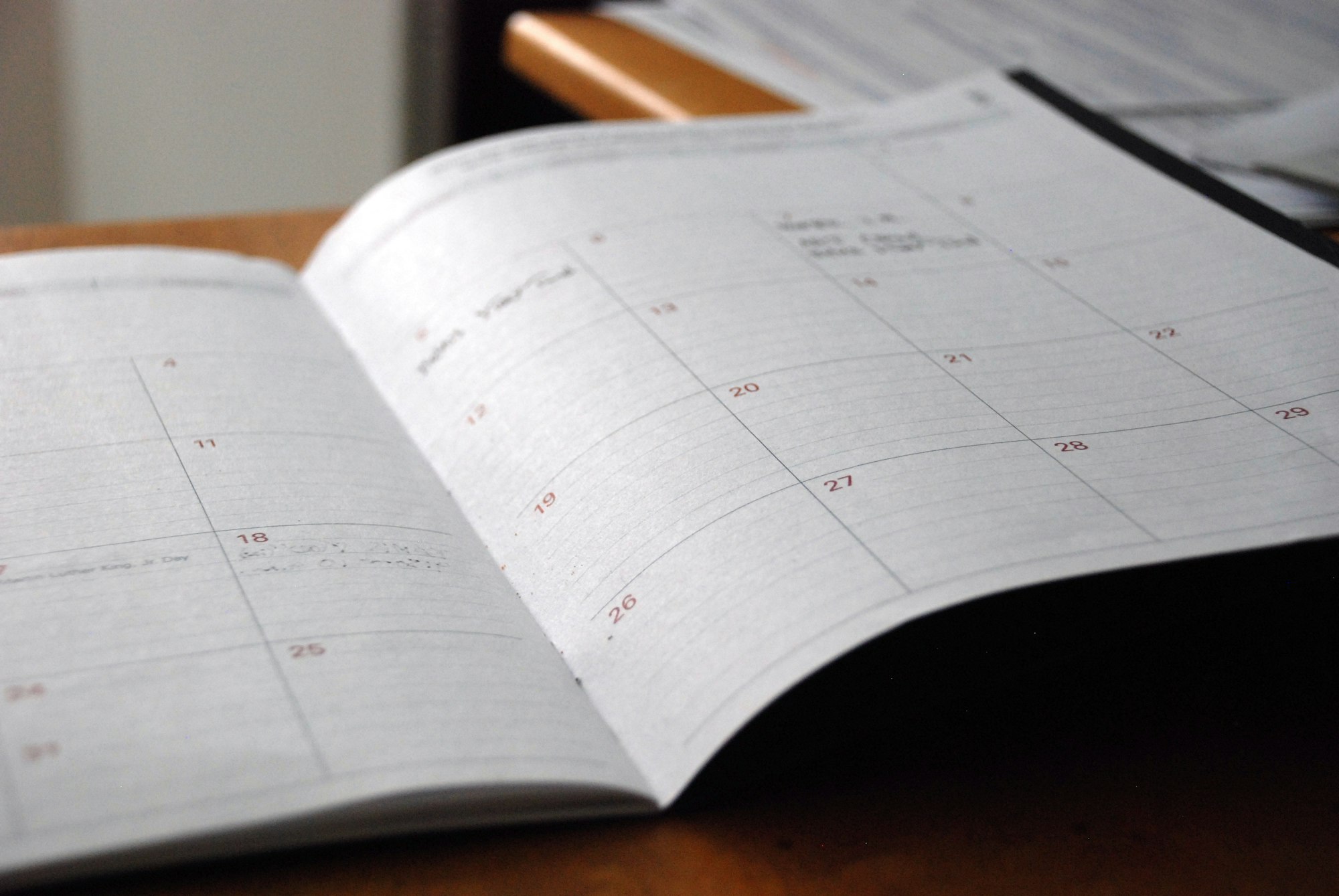 An open monthly planner on a wooden desk
