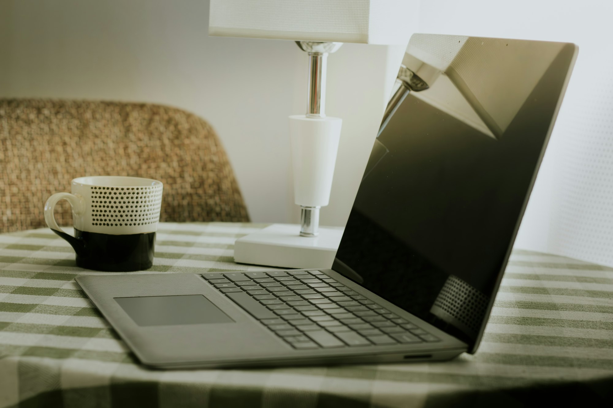 A laptop and a coffee cup on a checkered tablecloth