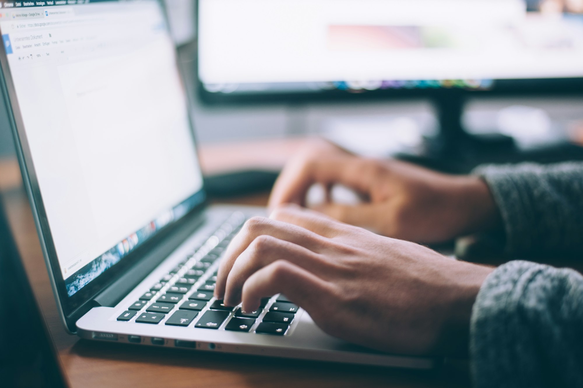 A person typing on a laptop at a desk
