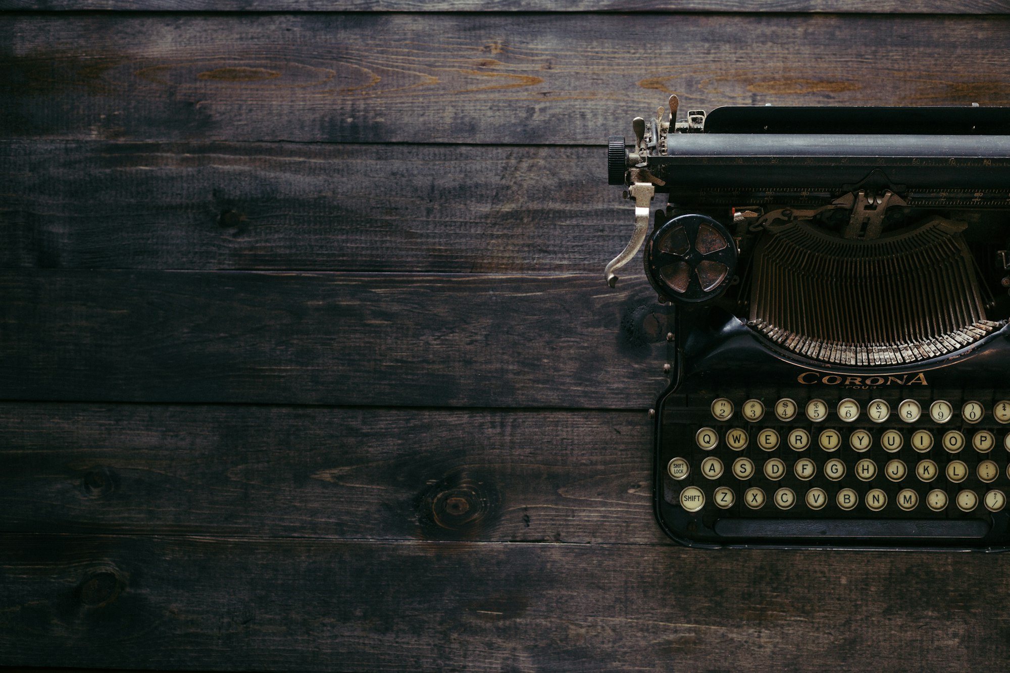 A black Corona typewriter on brown wood planks