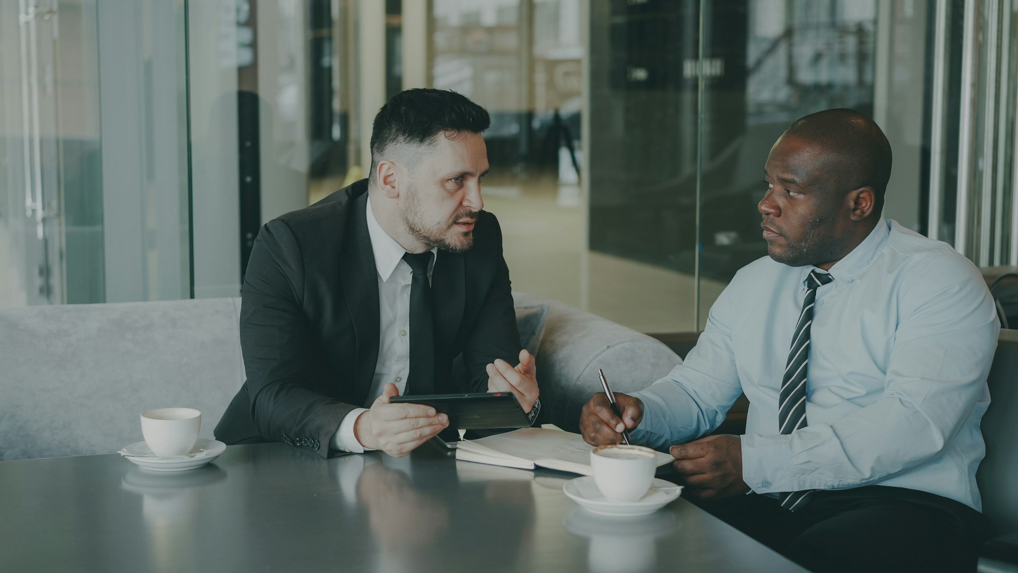 Two businessmen discussing work over coffee