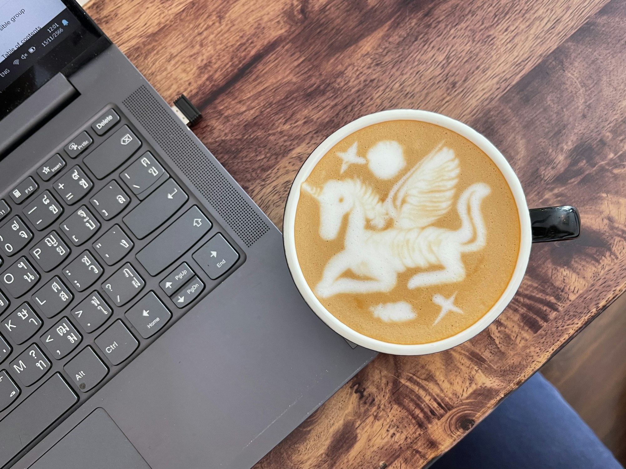 A cup of coffee sitting next to a laptop computer