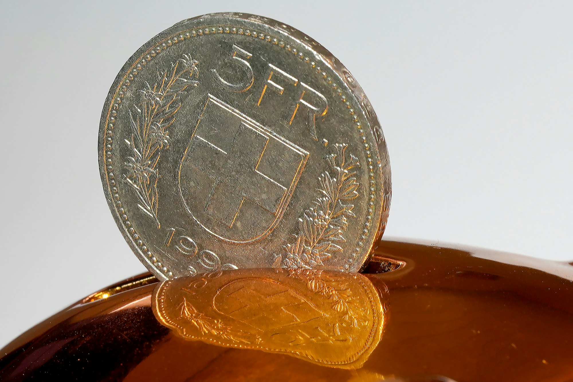 A coin being inserted into a piggy bank