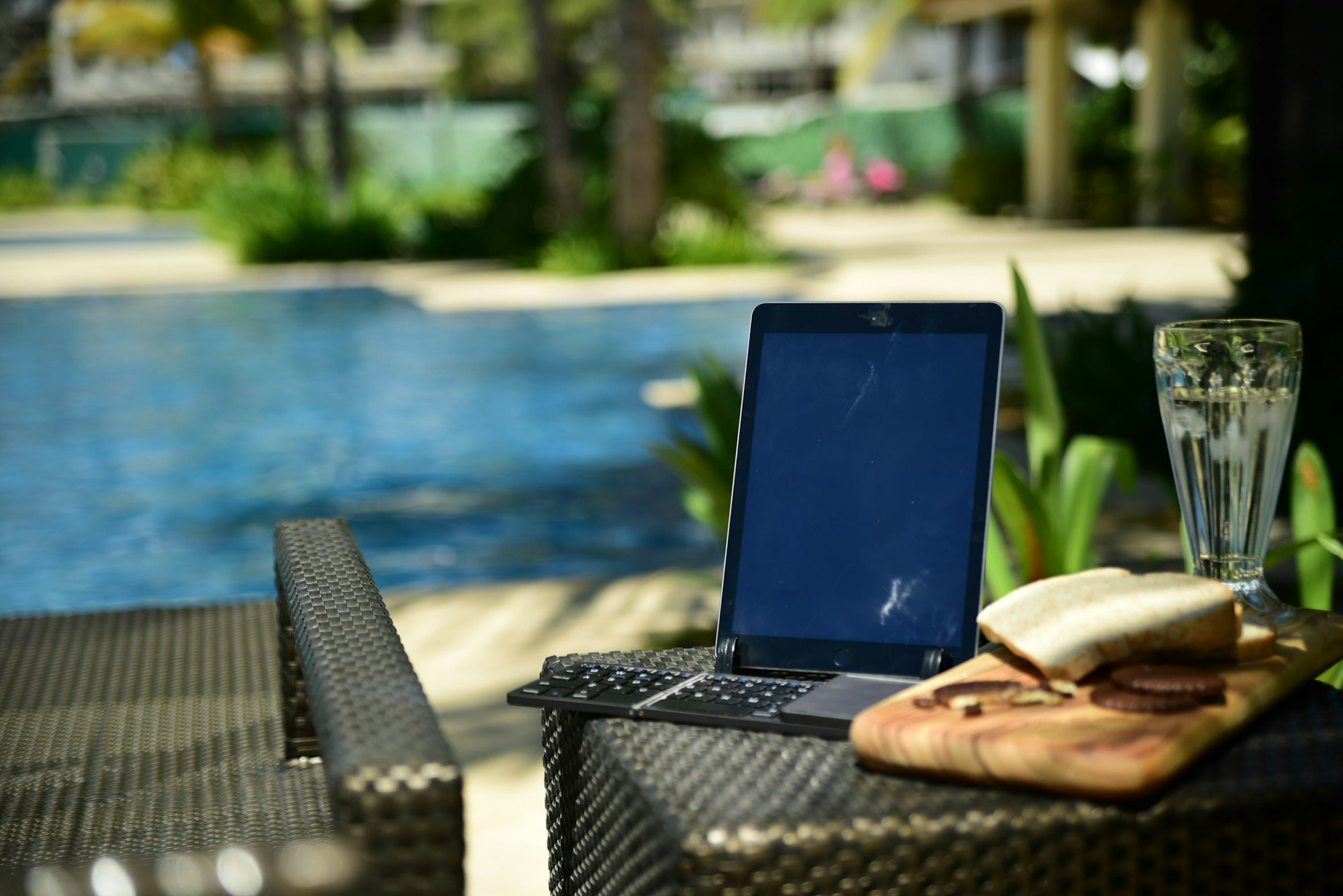 Laptop computer sitting on a table next to a pool, representing passive income