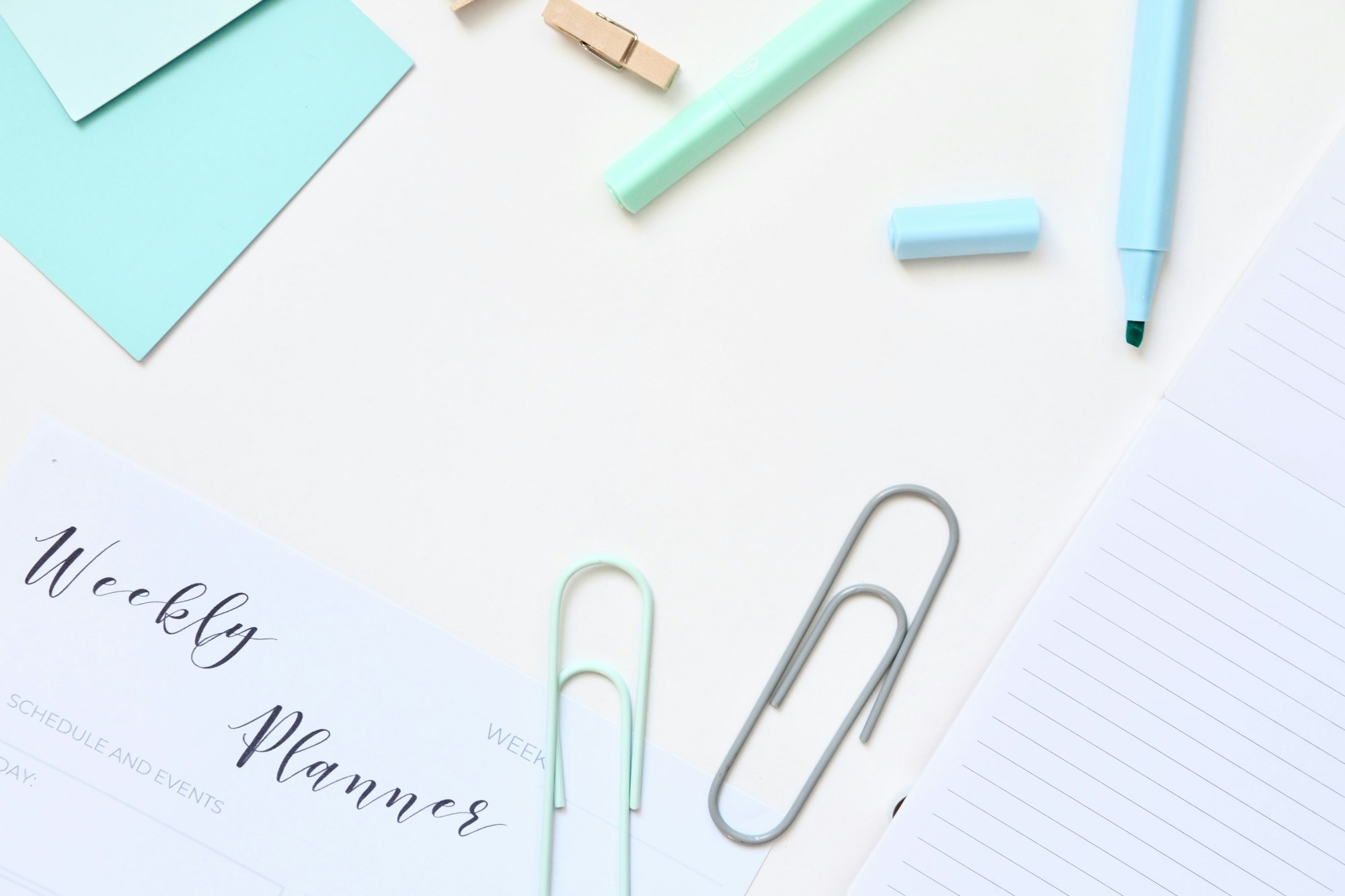 Weekly planner with desk supplies on a white surface