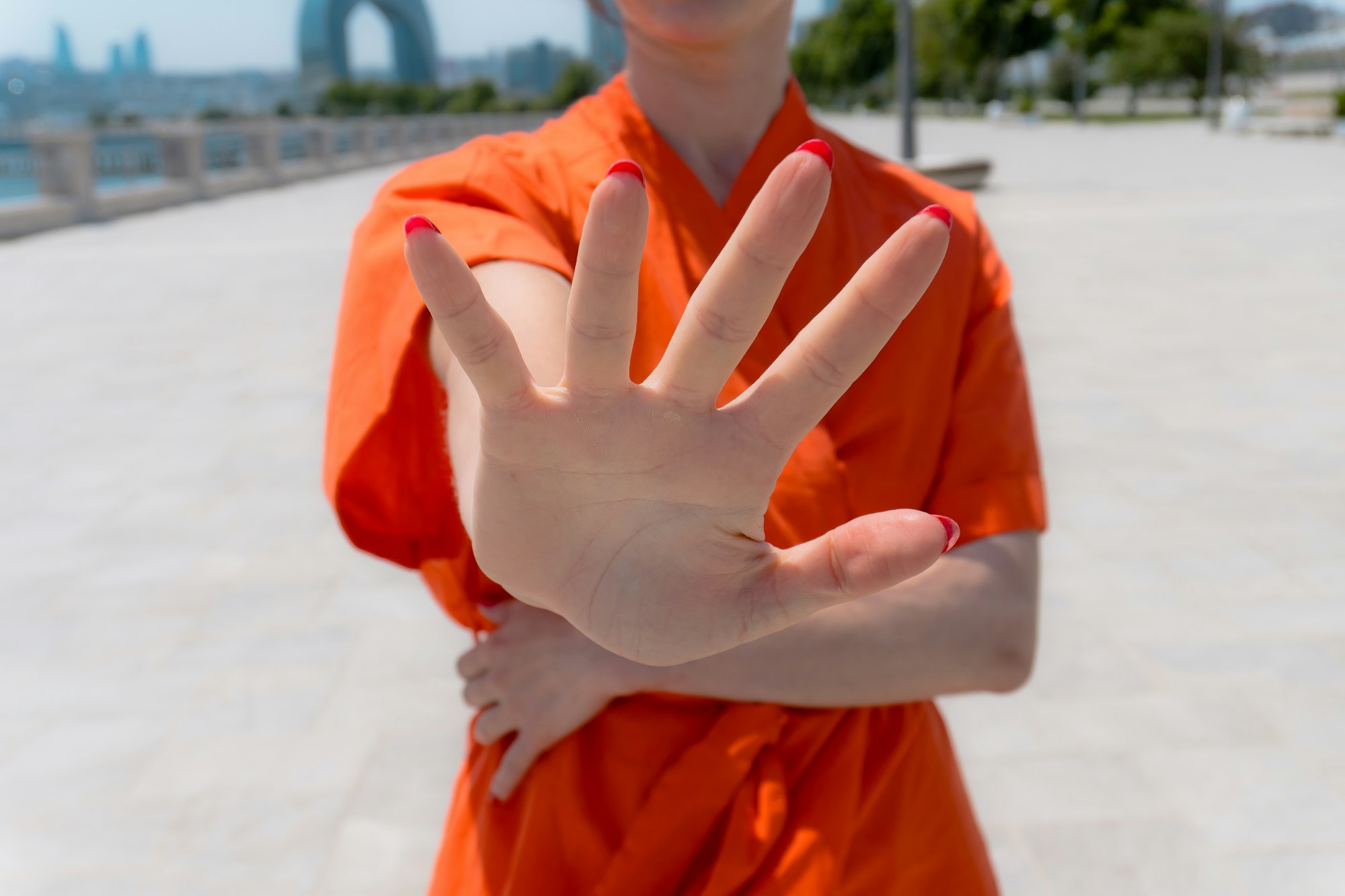 Woman in orange holding up hand in a stop gesture