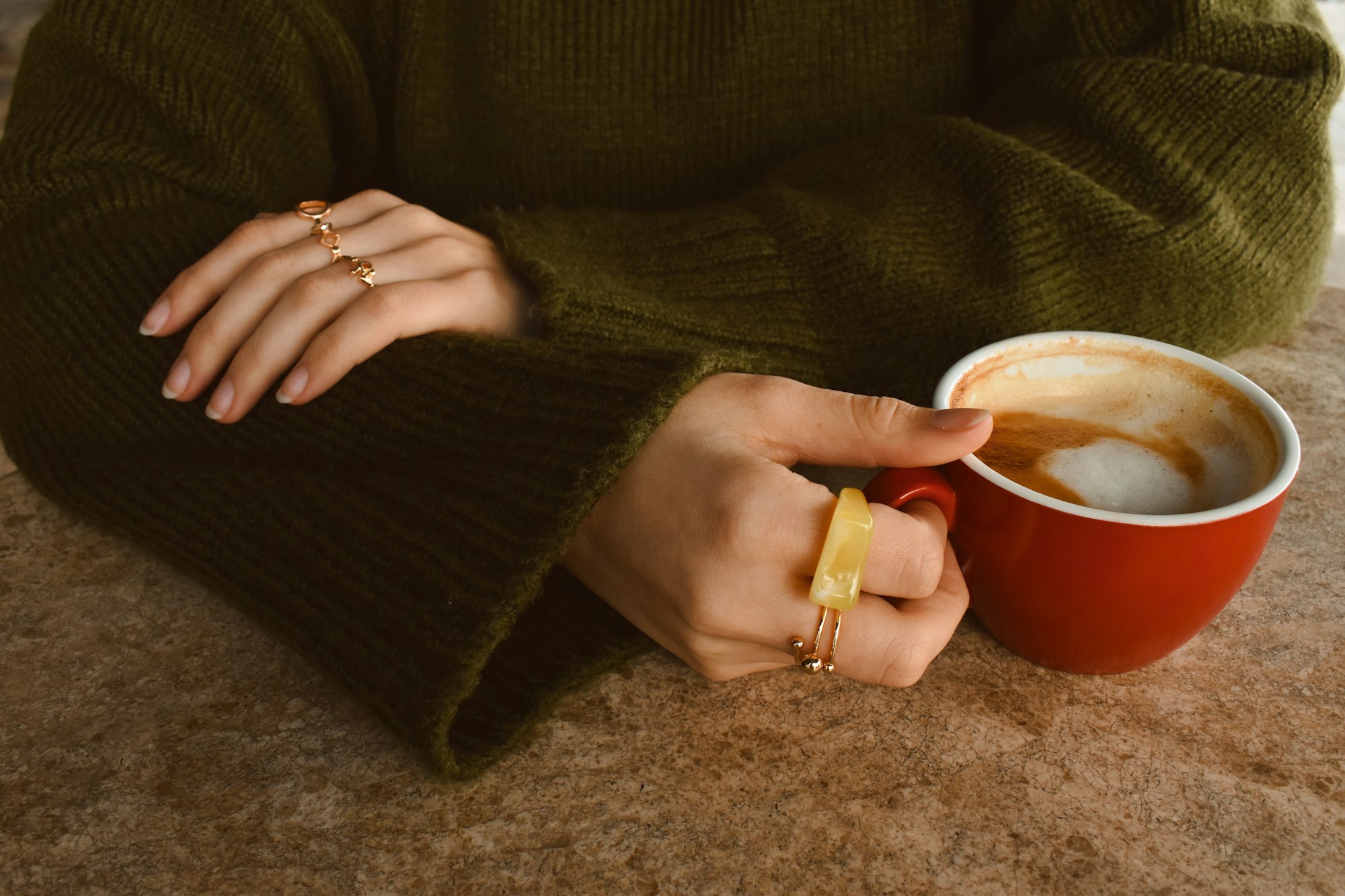 Woman holding a red cup of coffee with rings