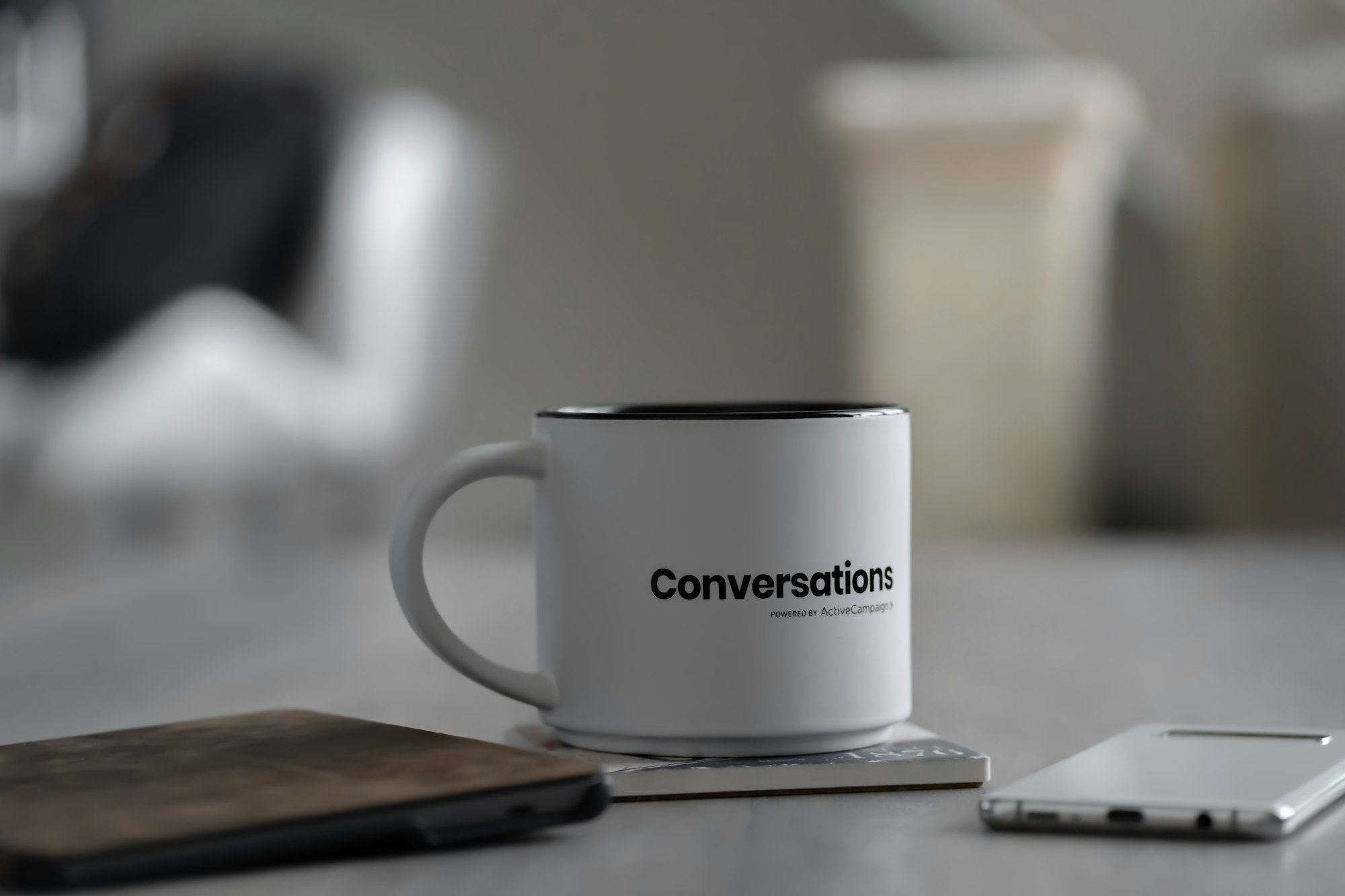 White conversations printed mug near smartphone