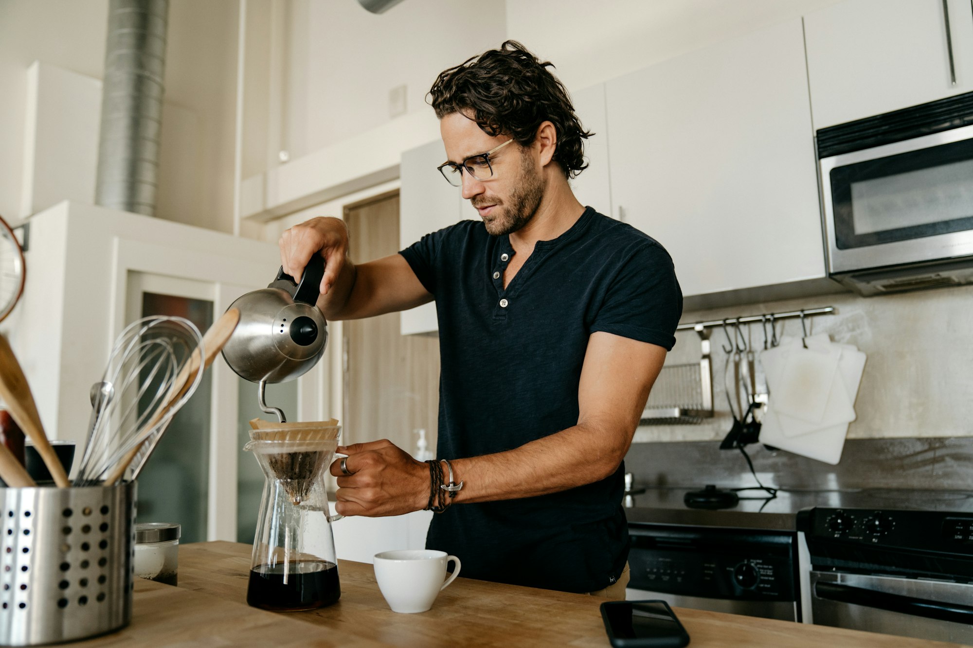 Man pouring morning coffee in a kitchen with a French press