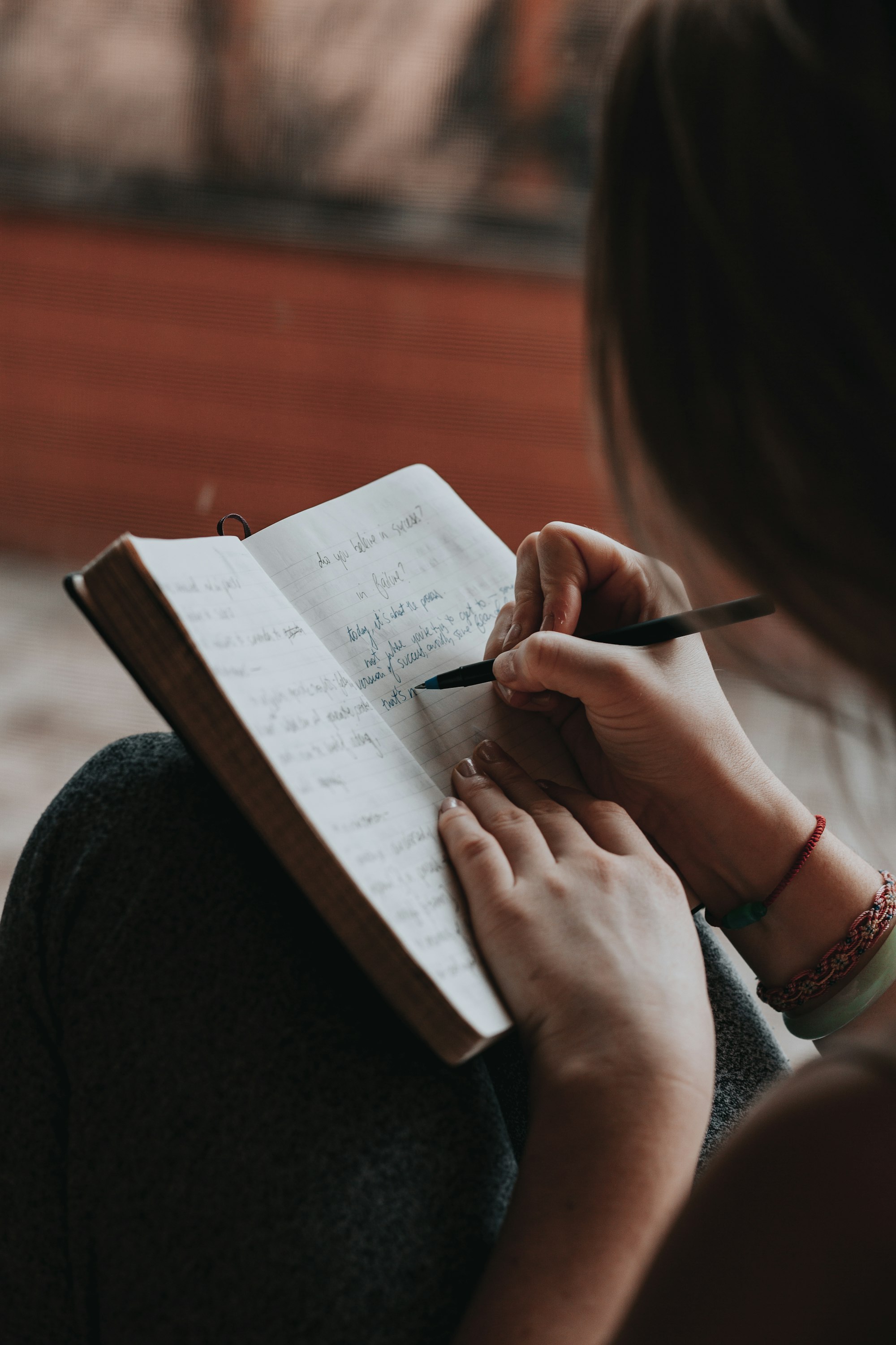 A person writing in a notebook with a pen