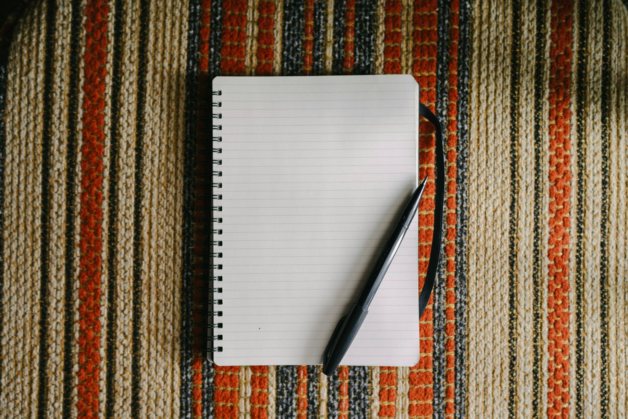 A blank notebook with a pen on striped fabric