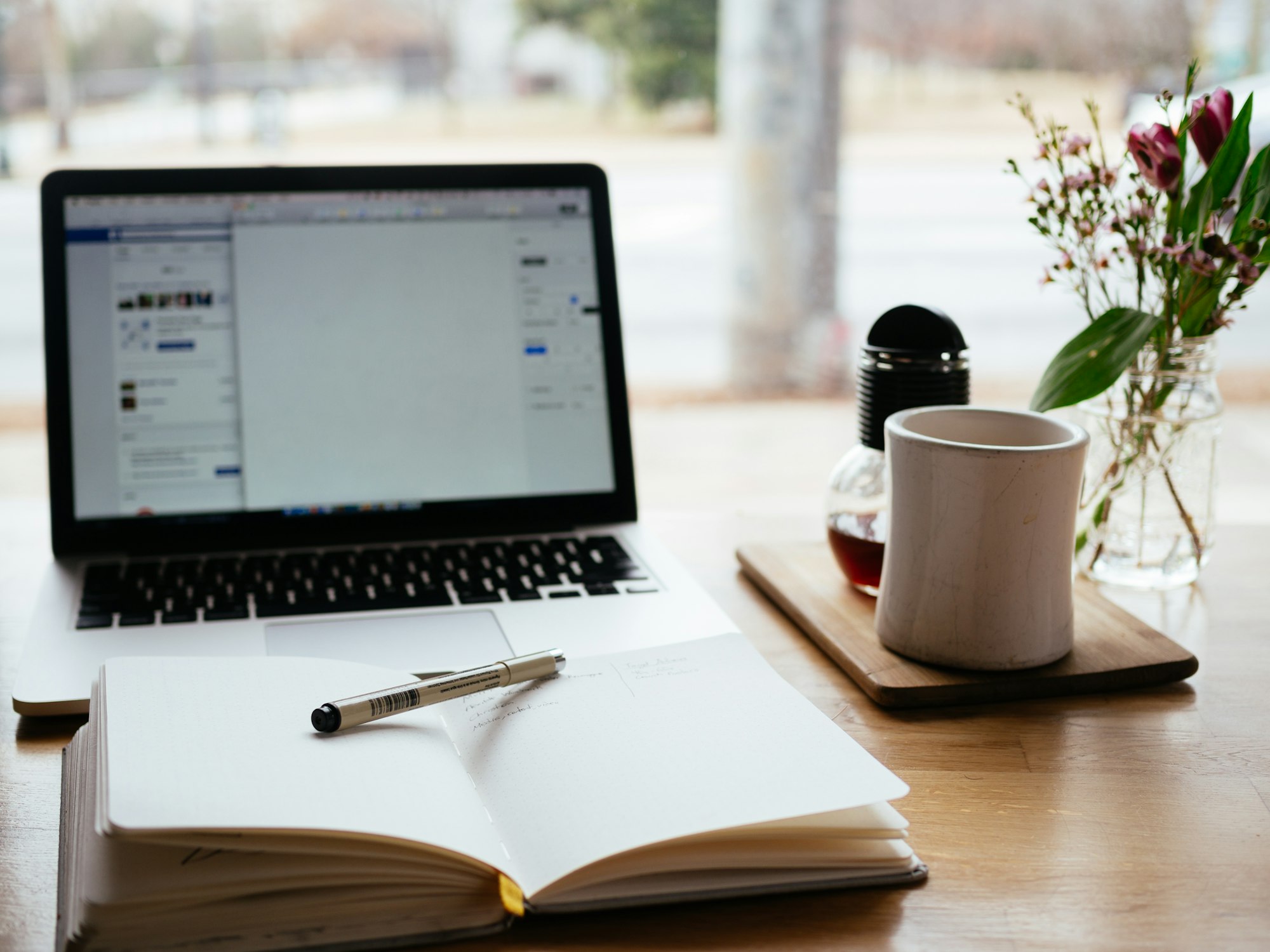 A laptop beside an open notebook on a desk