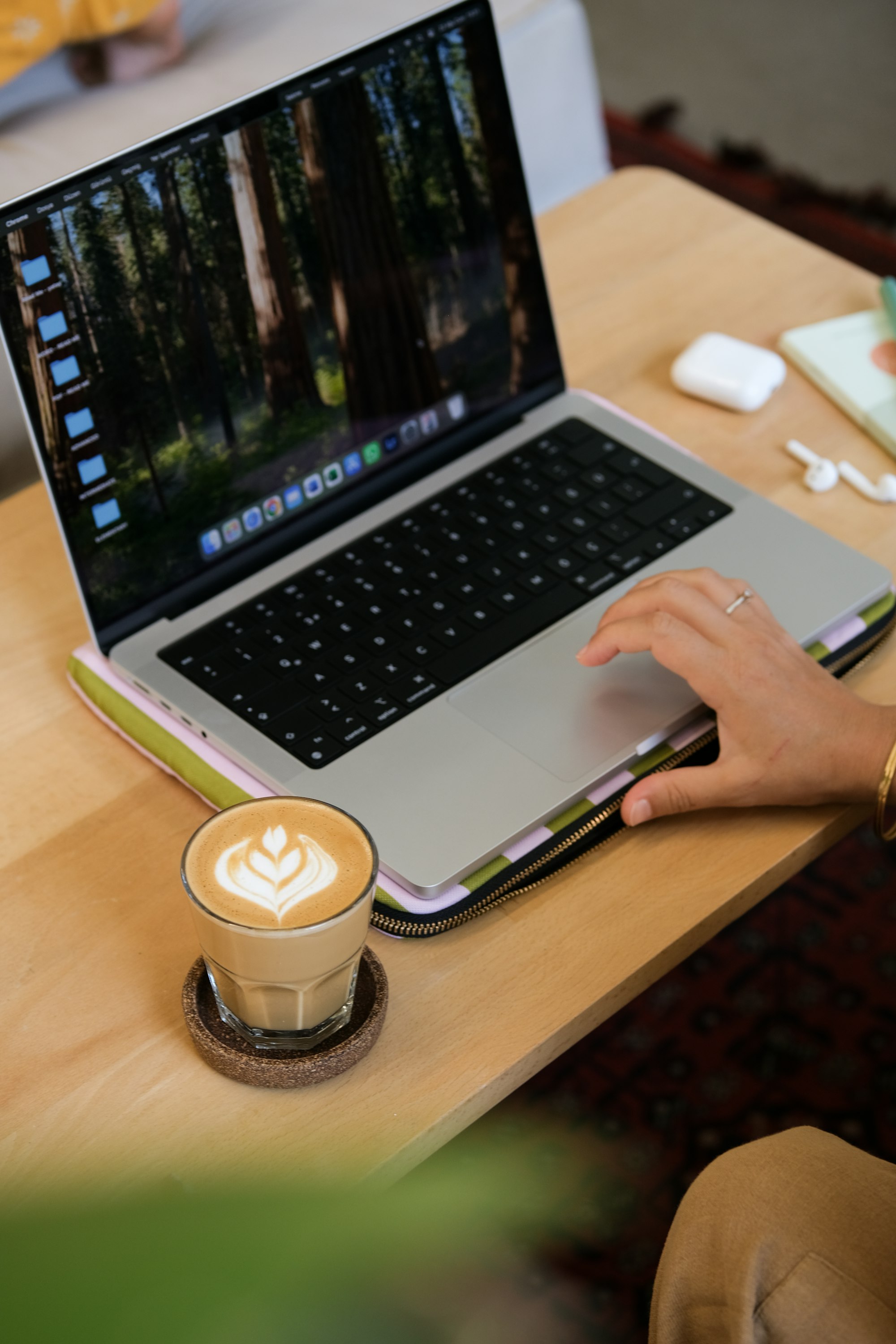Person working on laptop with latte art coffee