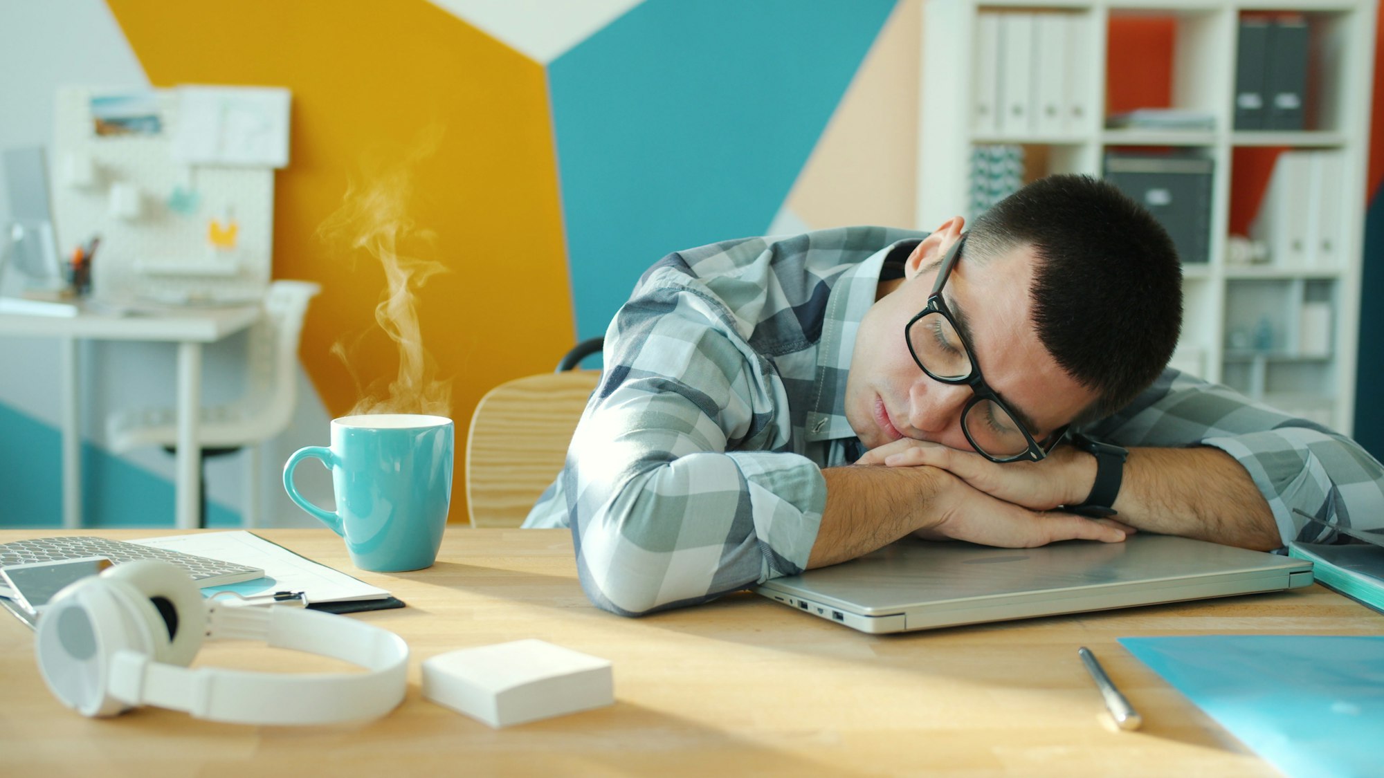 Man sleeping at desk with coffee and laptop