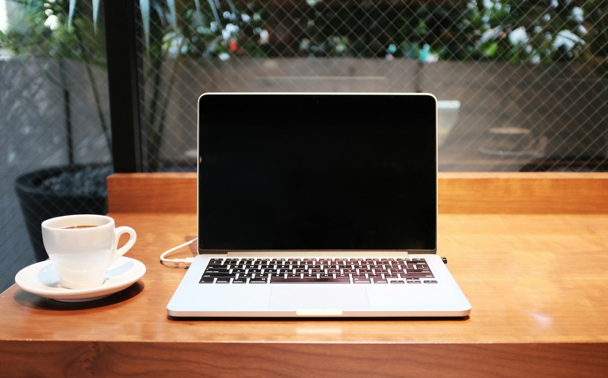 A laptop computer beside a coffee mug