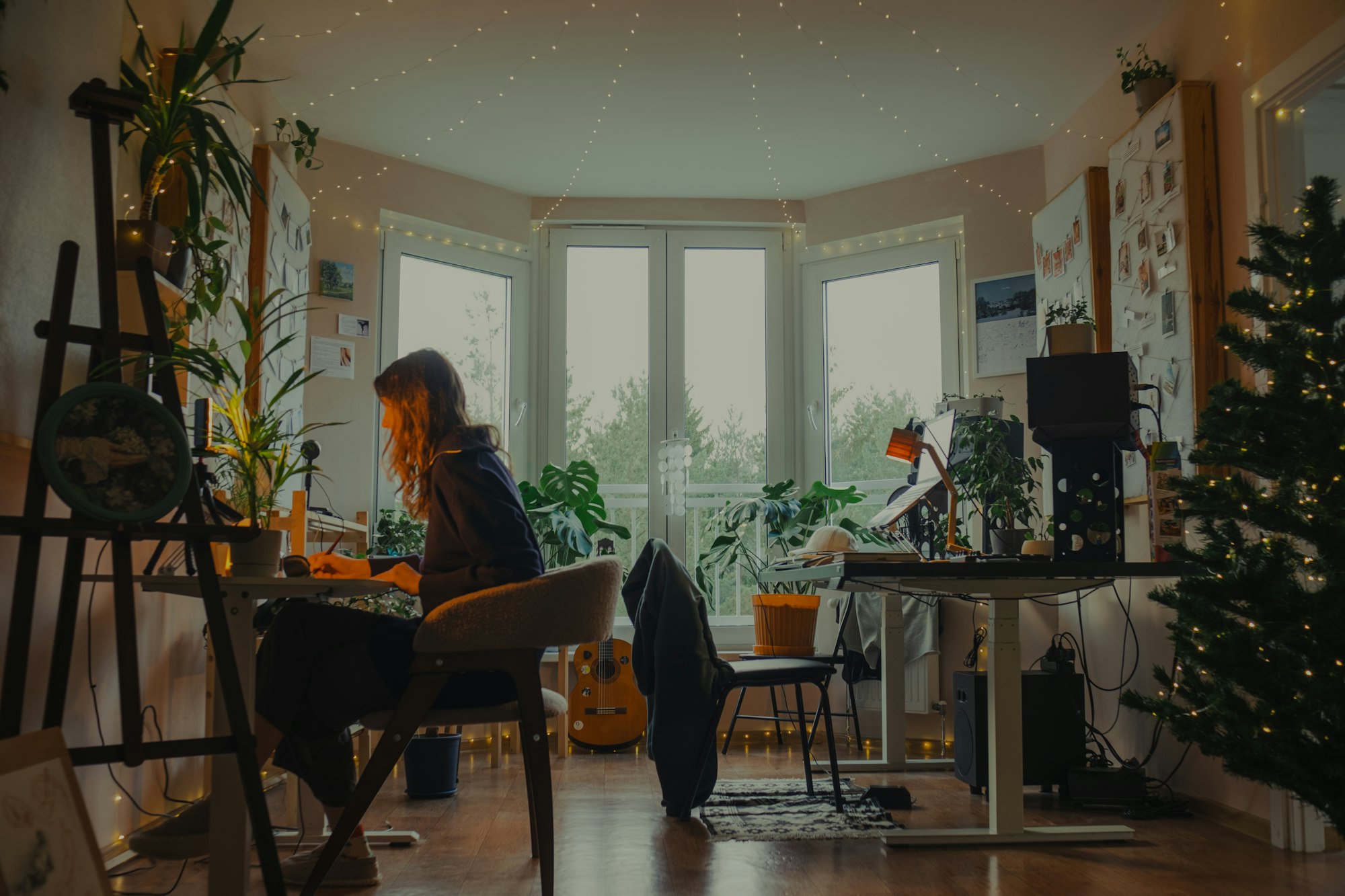 Woman working at a desk in a cozy plant-filled room