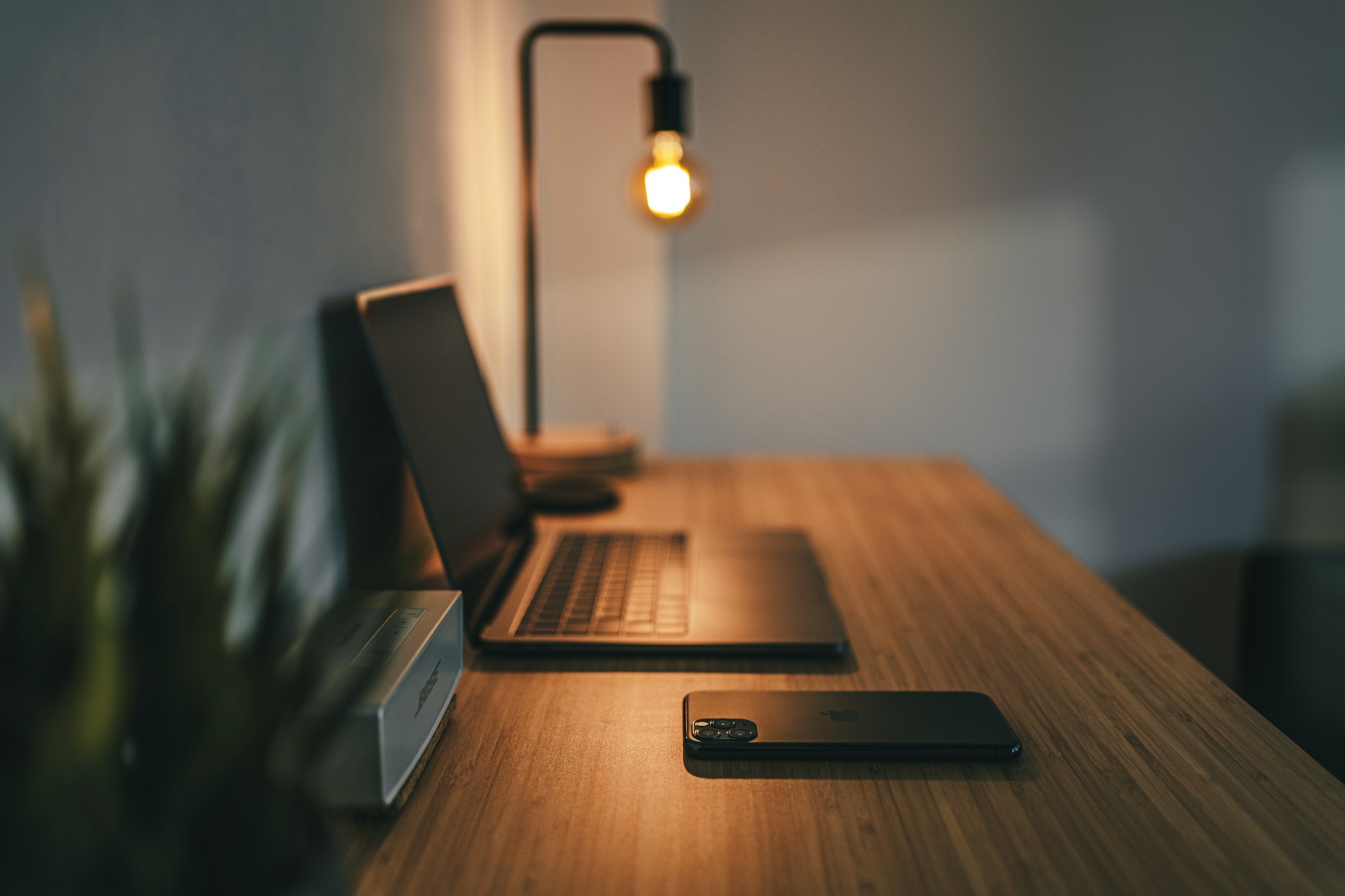 A dark empty desk with a laptop glowing faintly and an empty chair