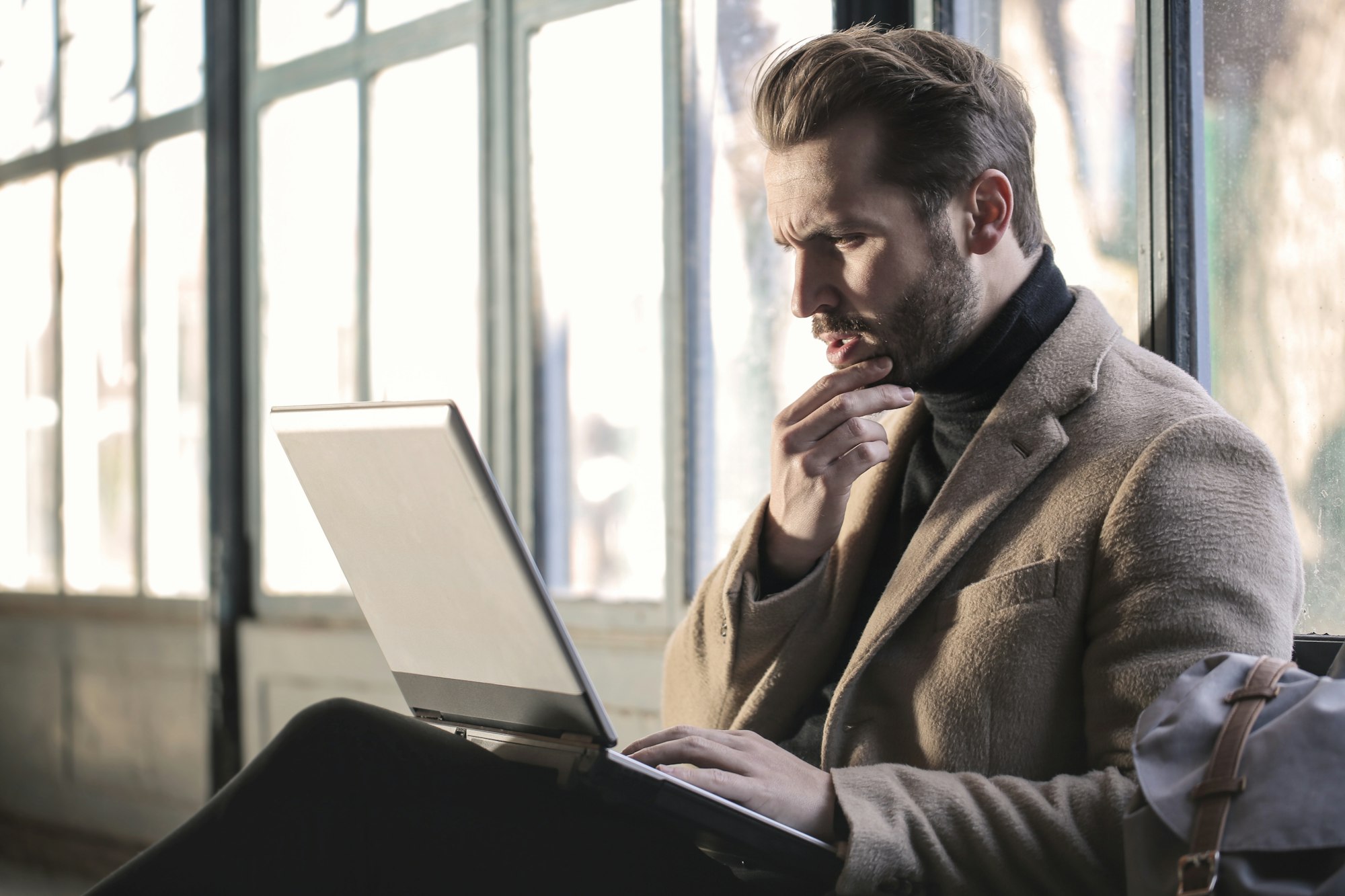 A person looking thoughtfully at a laptop screen