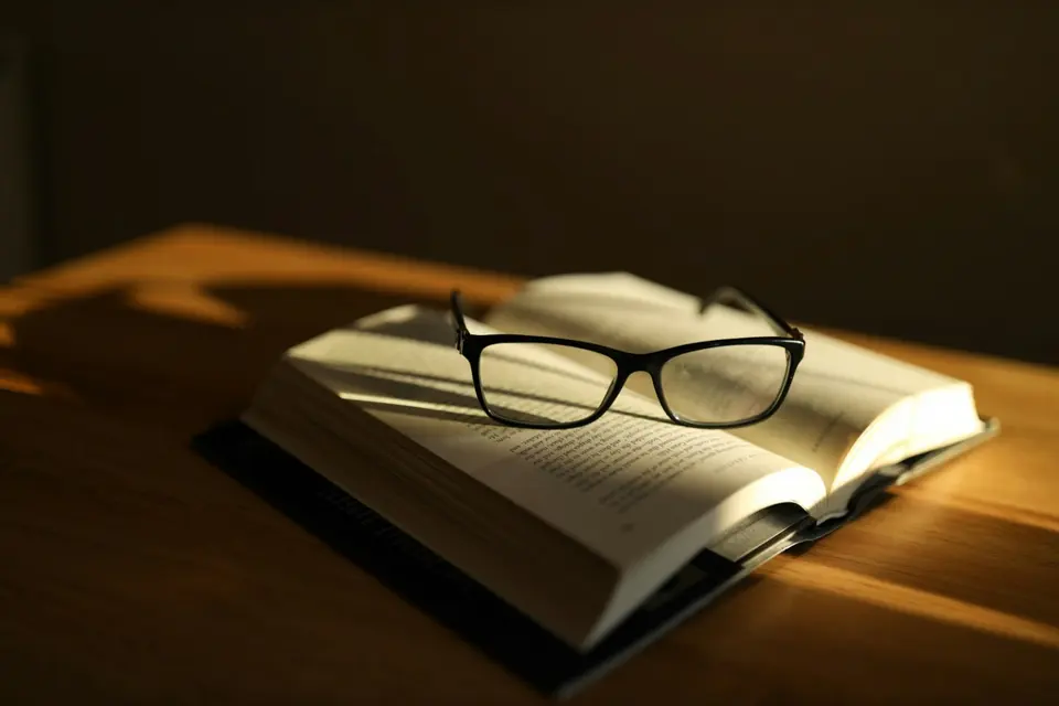 Black-framed glasses resting on an open book