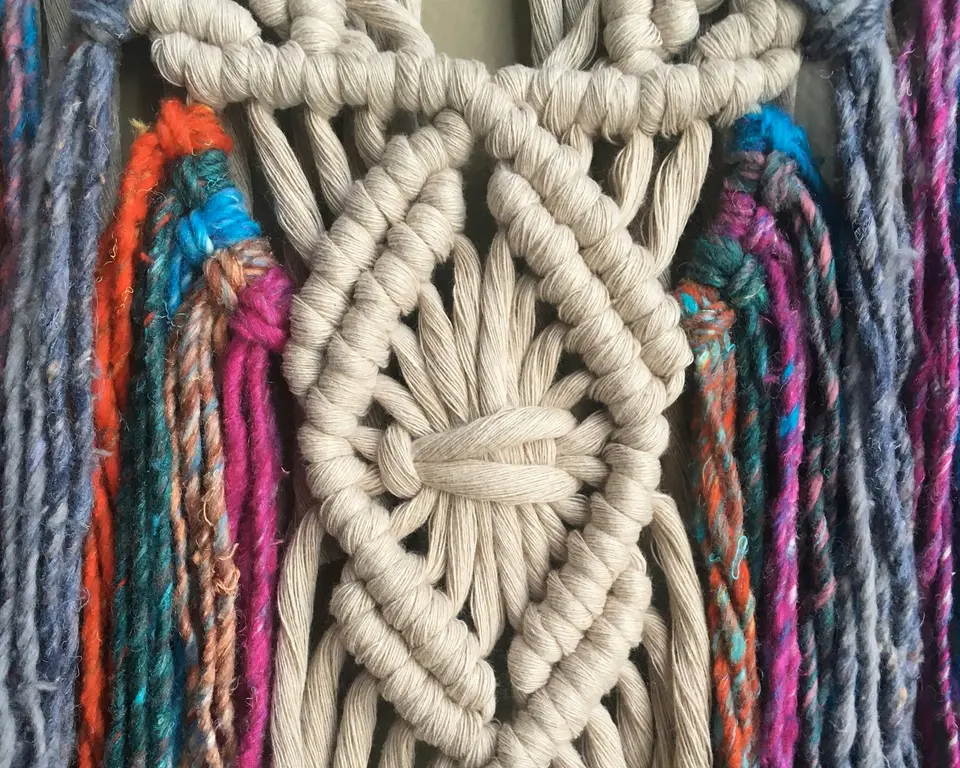 Knotted cream cord surrounded by strands of colored yarn