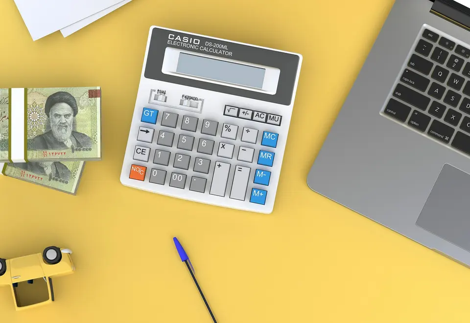 A calculator sitting on top of a desk next to a laptop