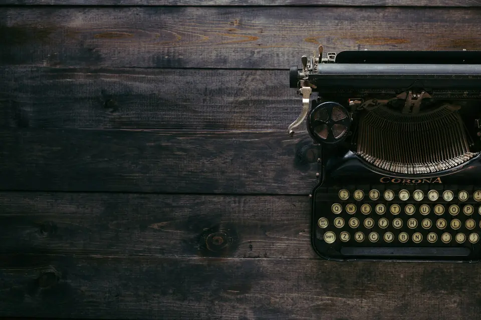 A black Corona typewriter on brown wood planks
