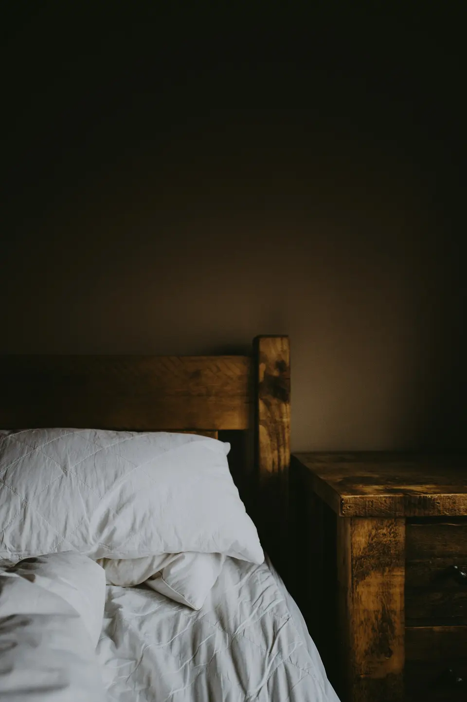 Brown wooden bed frame and nightstand in a cozy bedroom