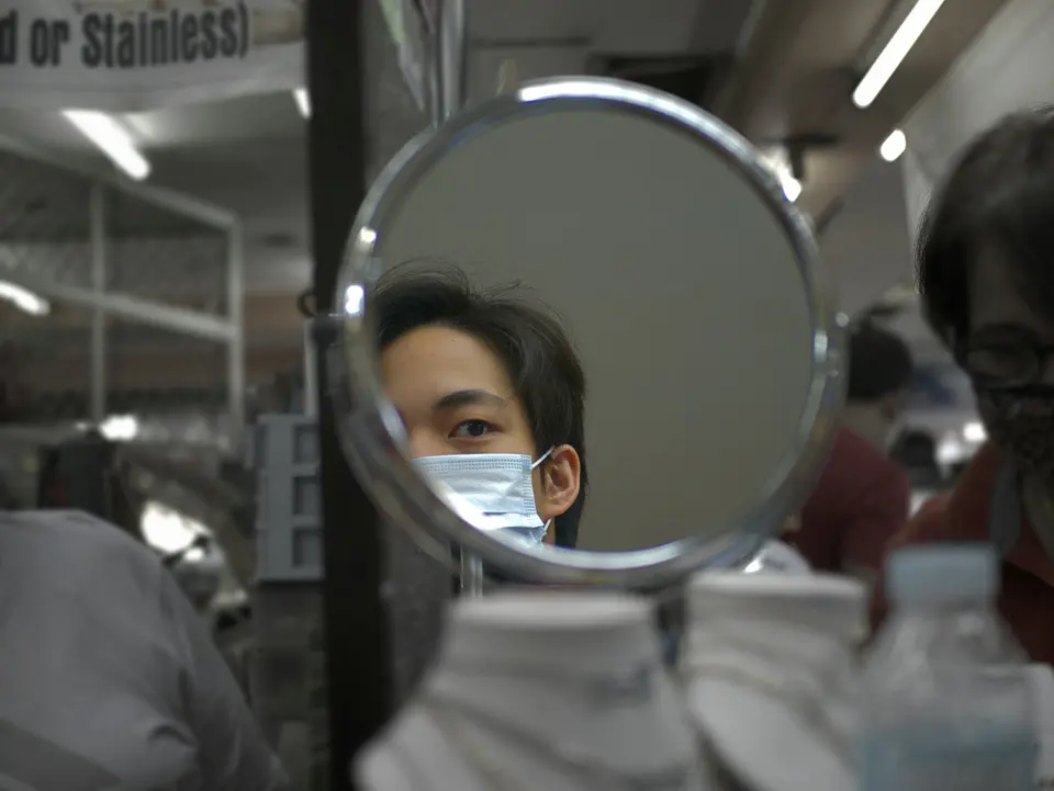 A person wearing a face mask reflected in a round mirror