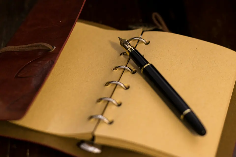 Fountain pen resting on an open ring-bound notebook