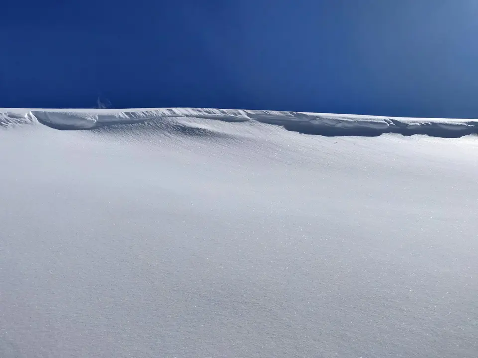 Snow-covered ridge beneath a clear blue sky