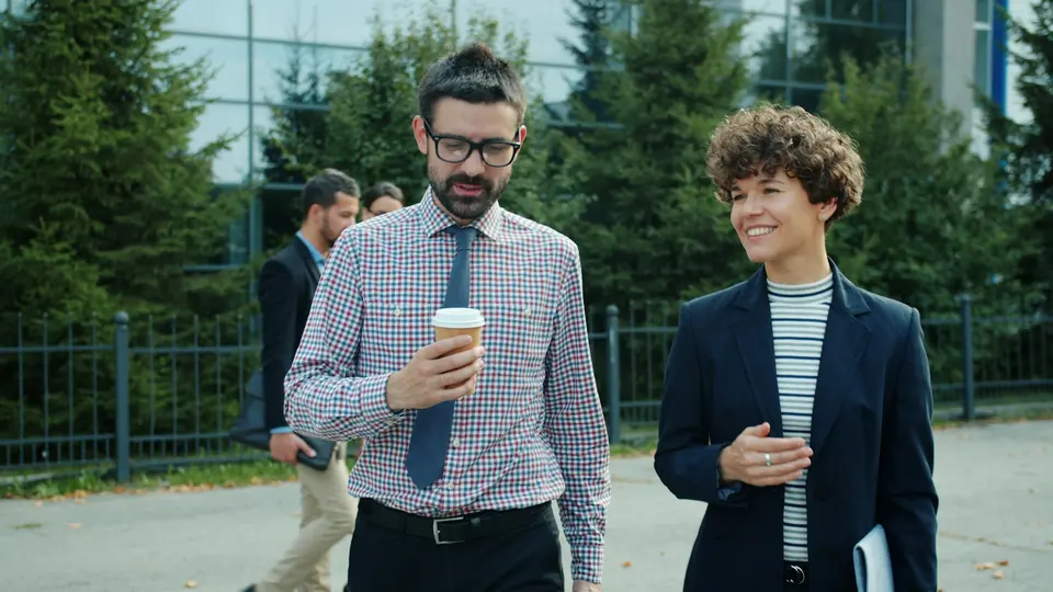 Two colleagues walking and talking outside an office building