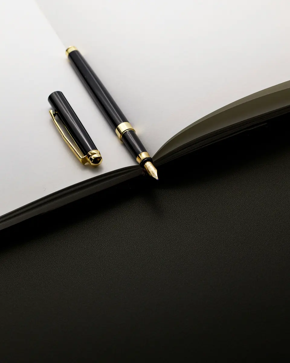 A black and gold pen resting on an open notebook
