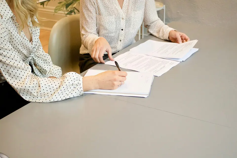 Two people signing paperwork at a table
