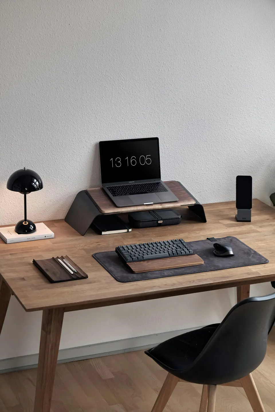 Laptop on a raised stand above a keyboard and mouse on a wooden desk