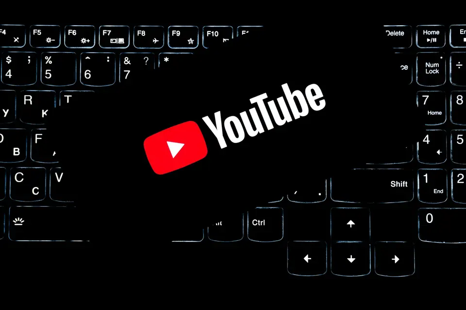 A phone displaying the YouTube logo over a computer keyboard